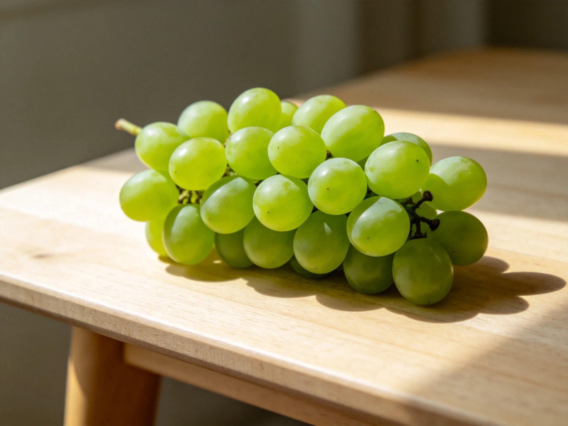 Fresh green grapes clustered on a light wooden table
