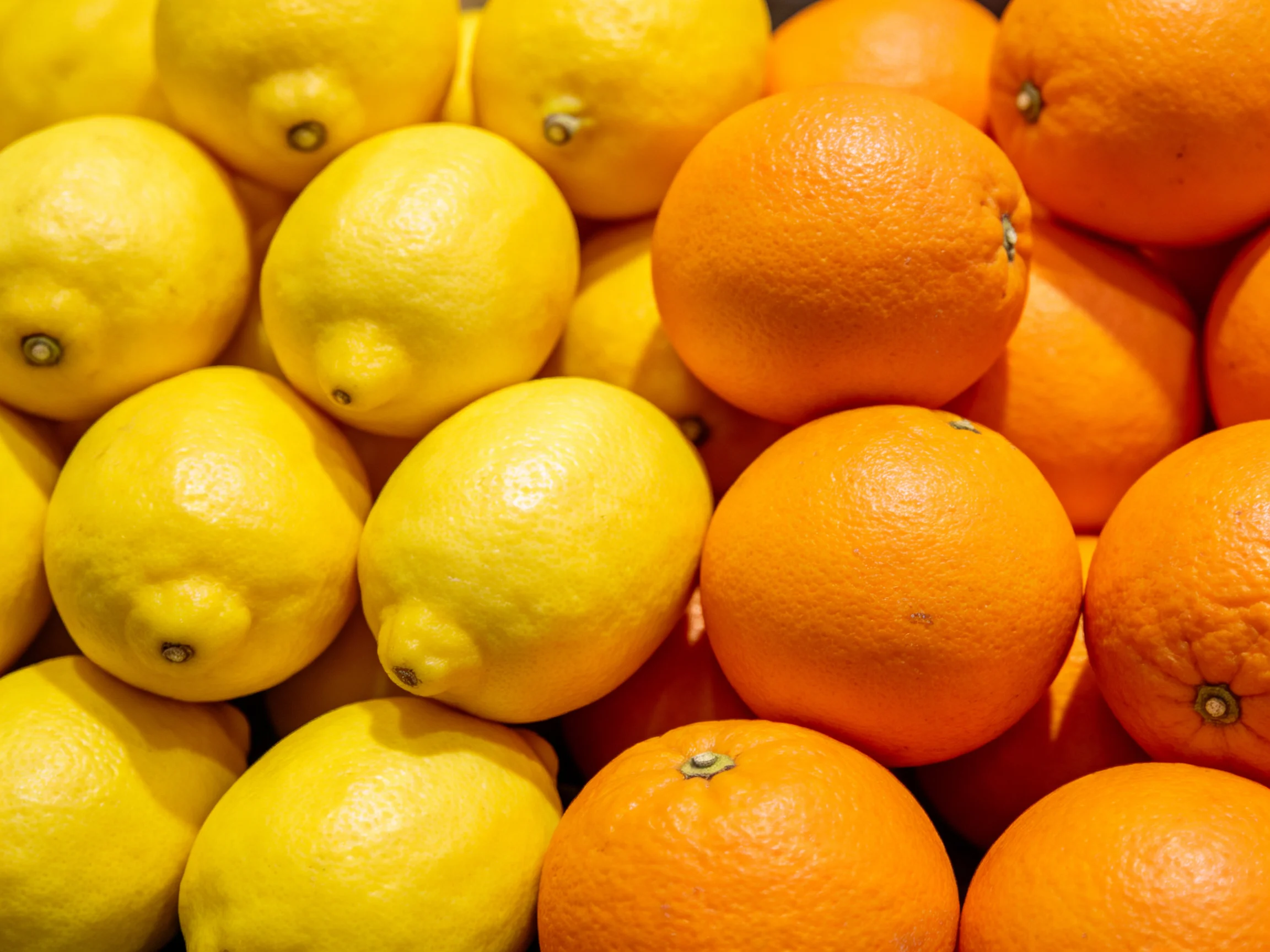 Fresh yellow lemons and vibrant orange oranges stacked together