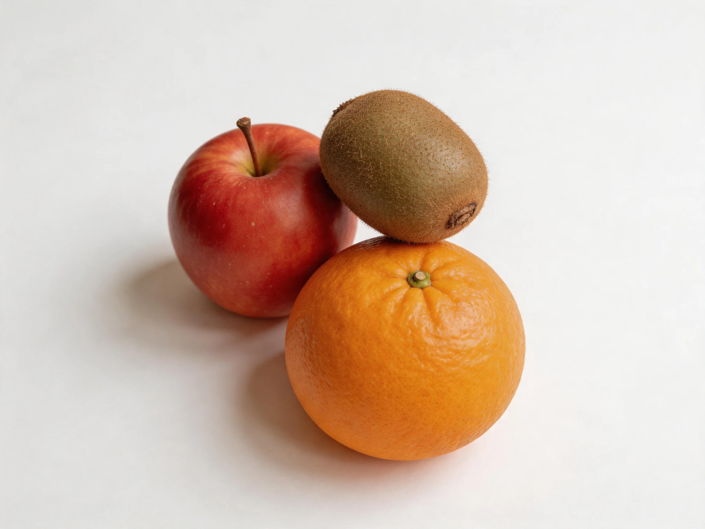 Three assorted fruits—red apple, brown kiwi, orange—are arranged together