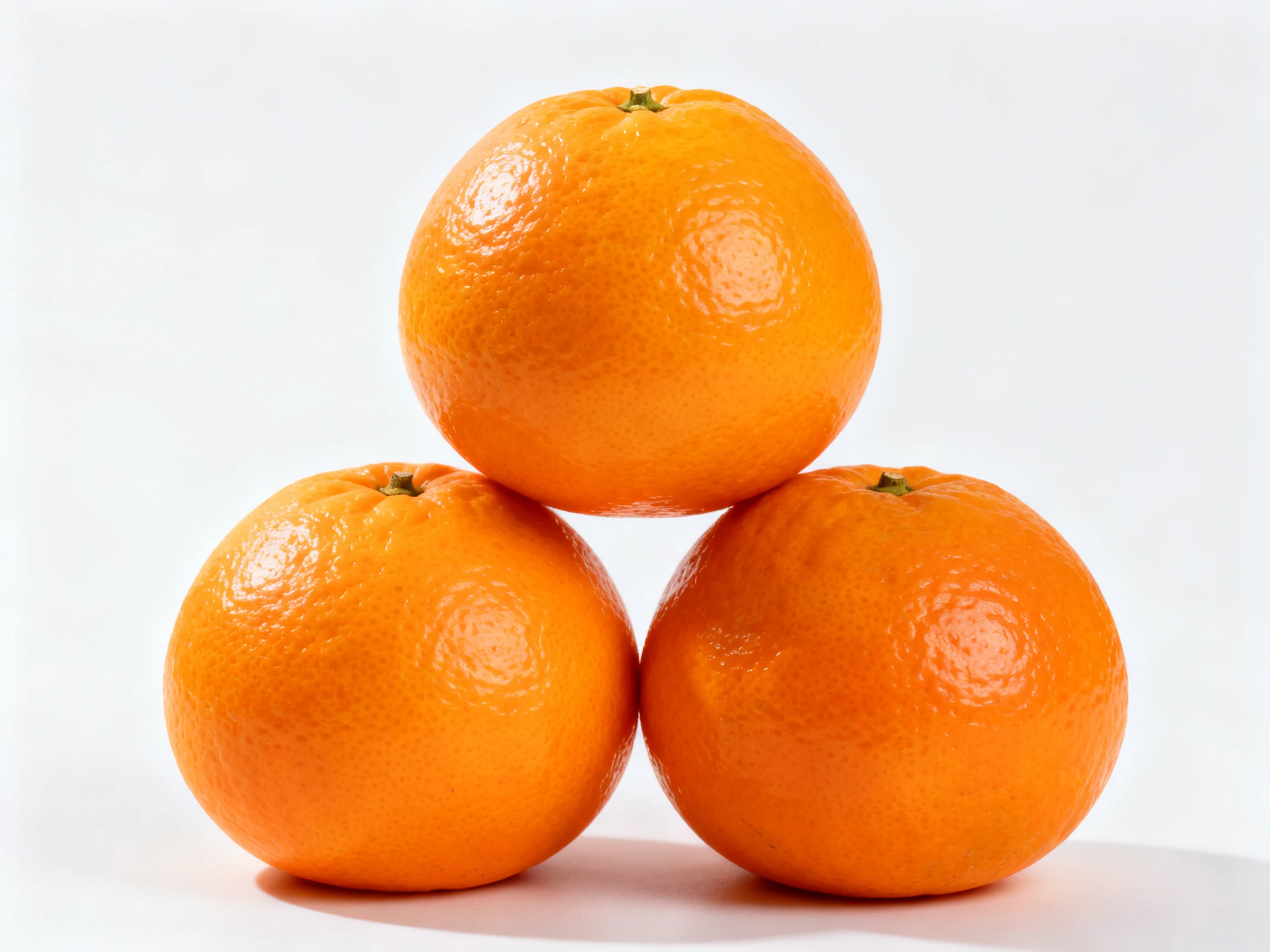 Three bright orange citrus fruits arranged in a triangular formation