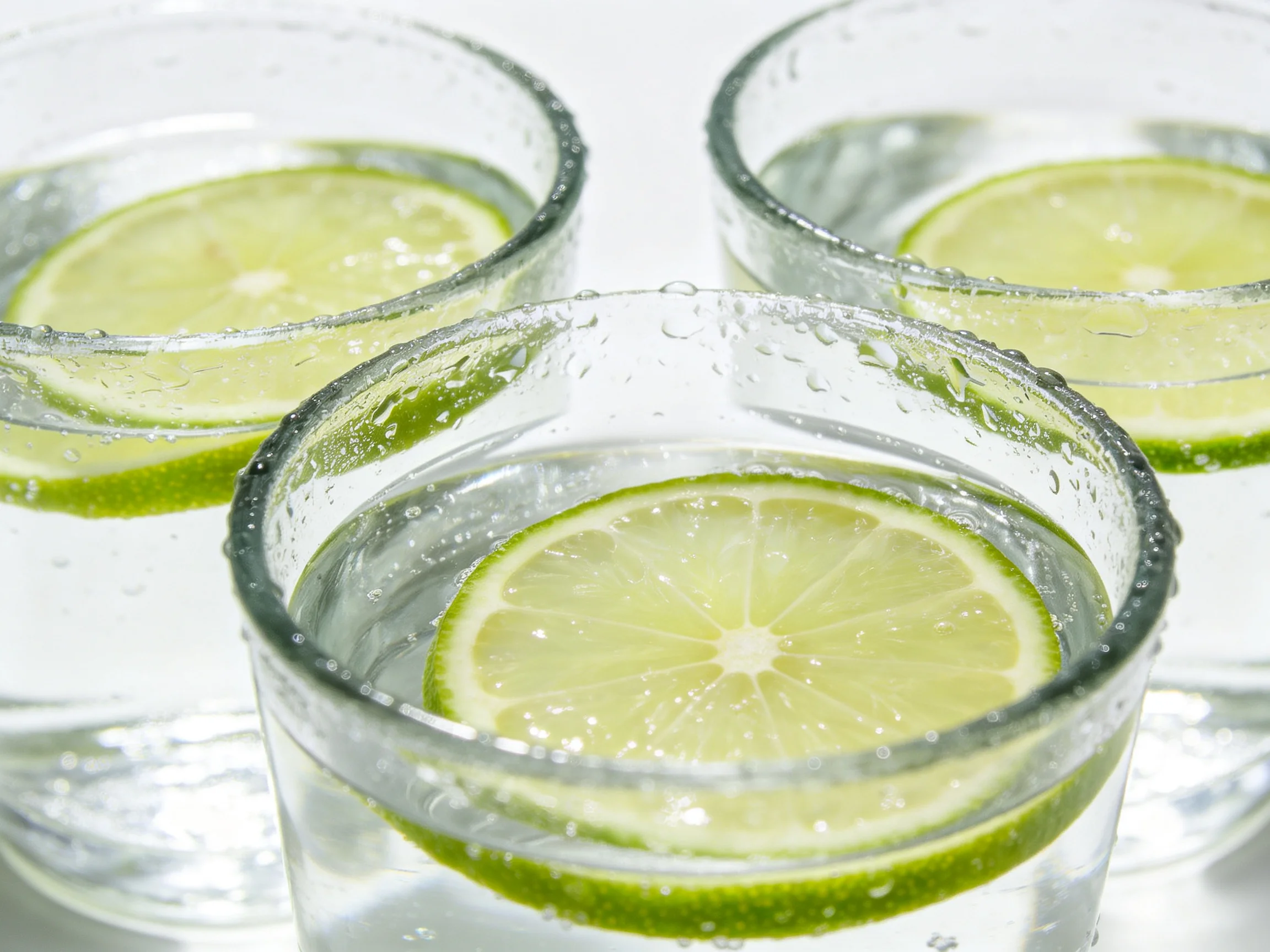 Three glass cups filled with clear water and lime slices