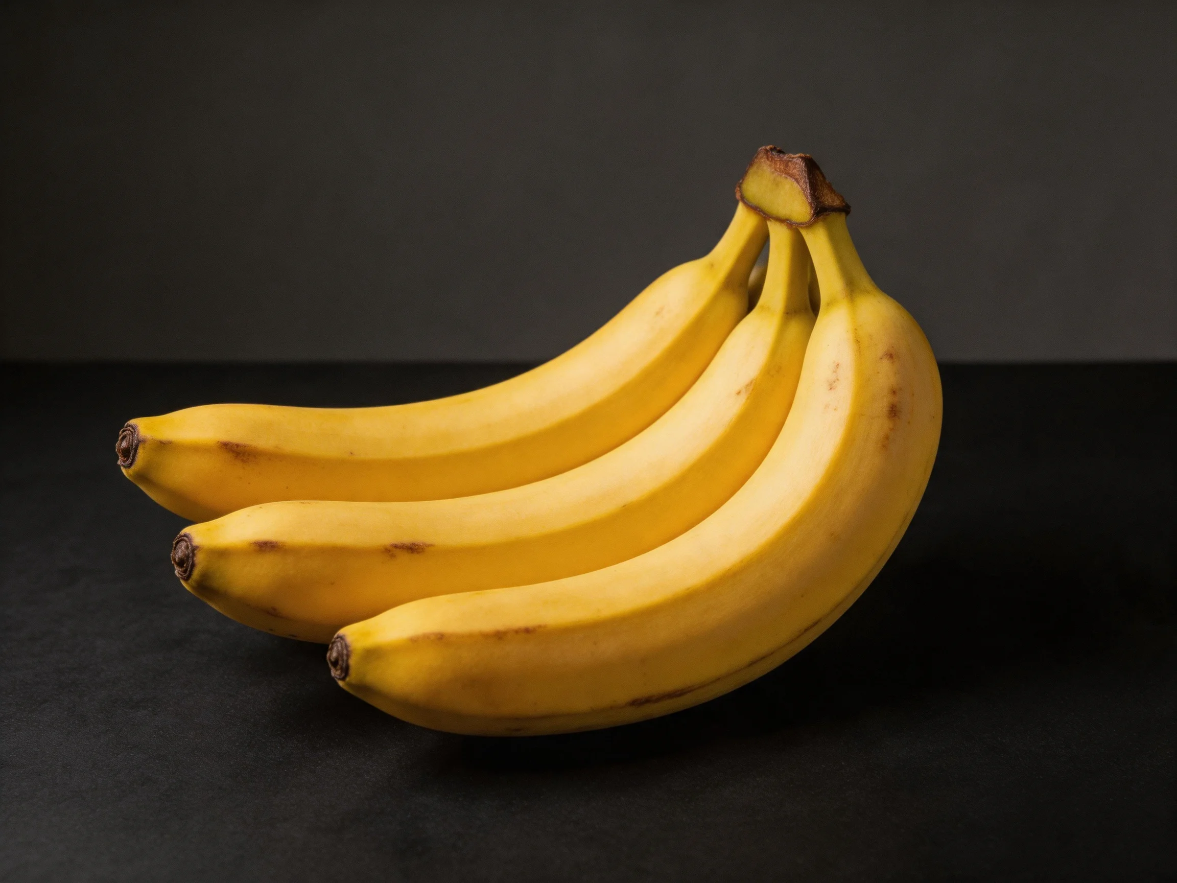 Three ripe yellow bananas clustered together