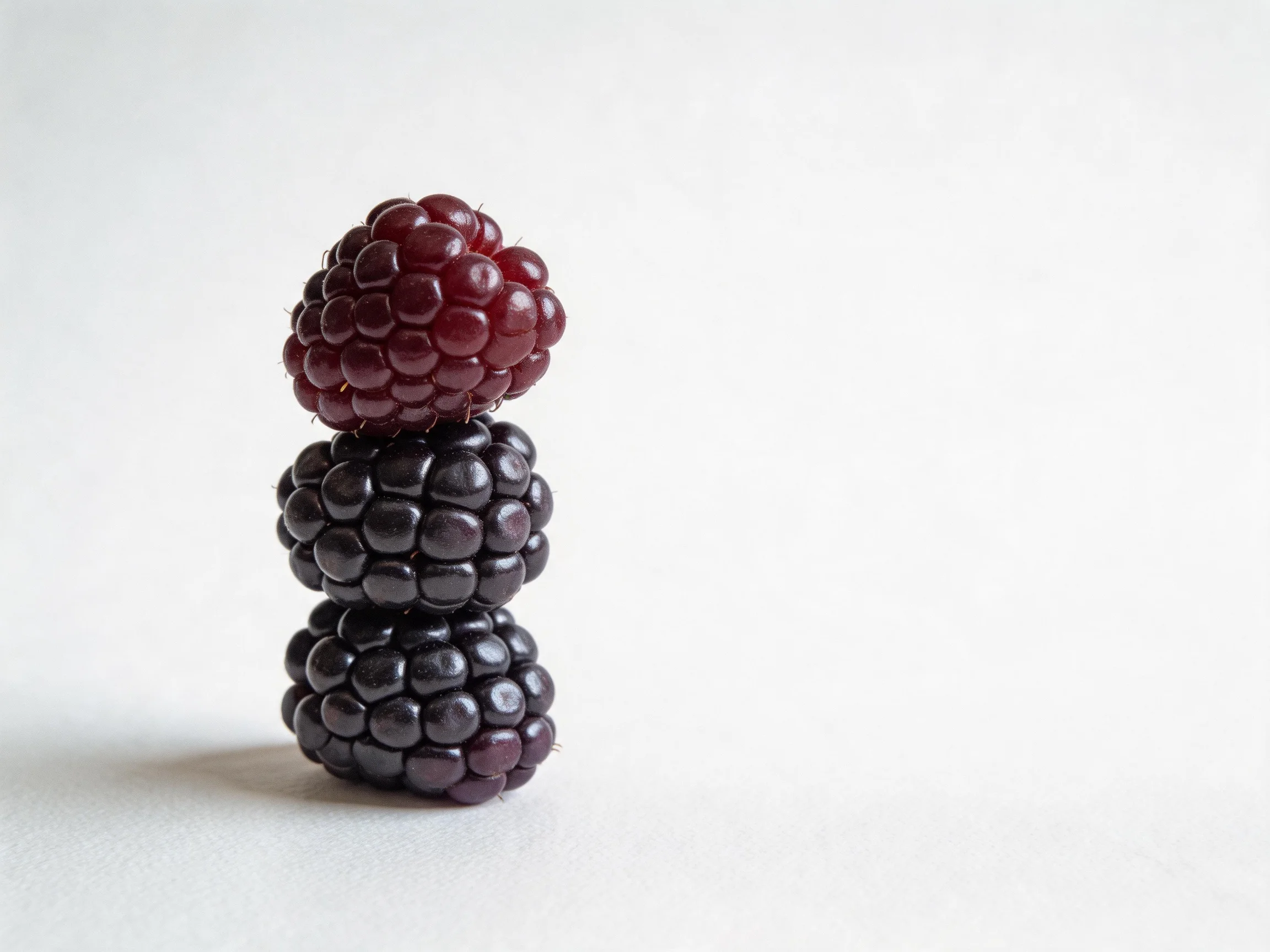 Three stacked berries exhibit rich red and dark purple hues