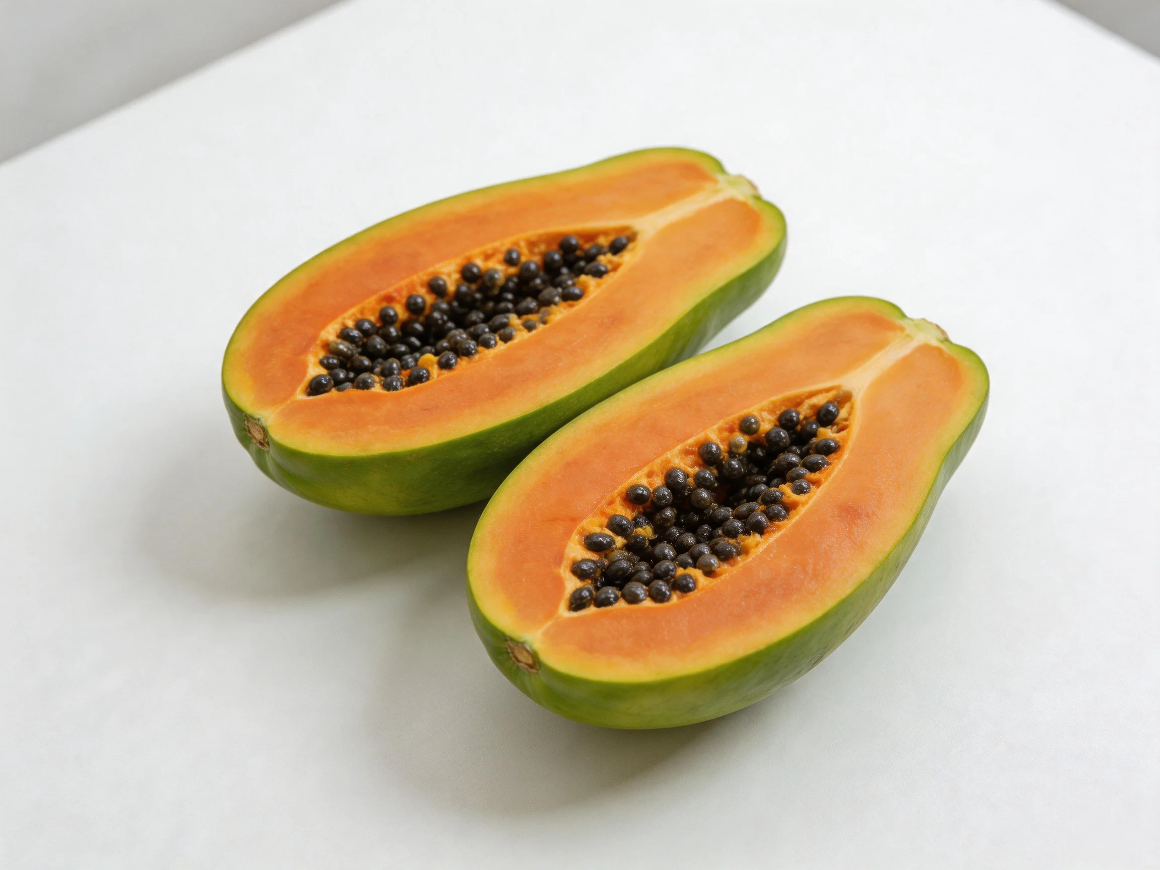 Two halved papayas display vibrant orange flesh and dark seeds