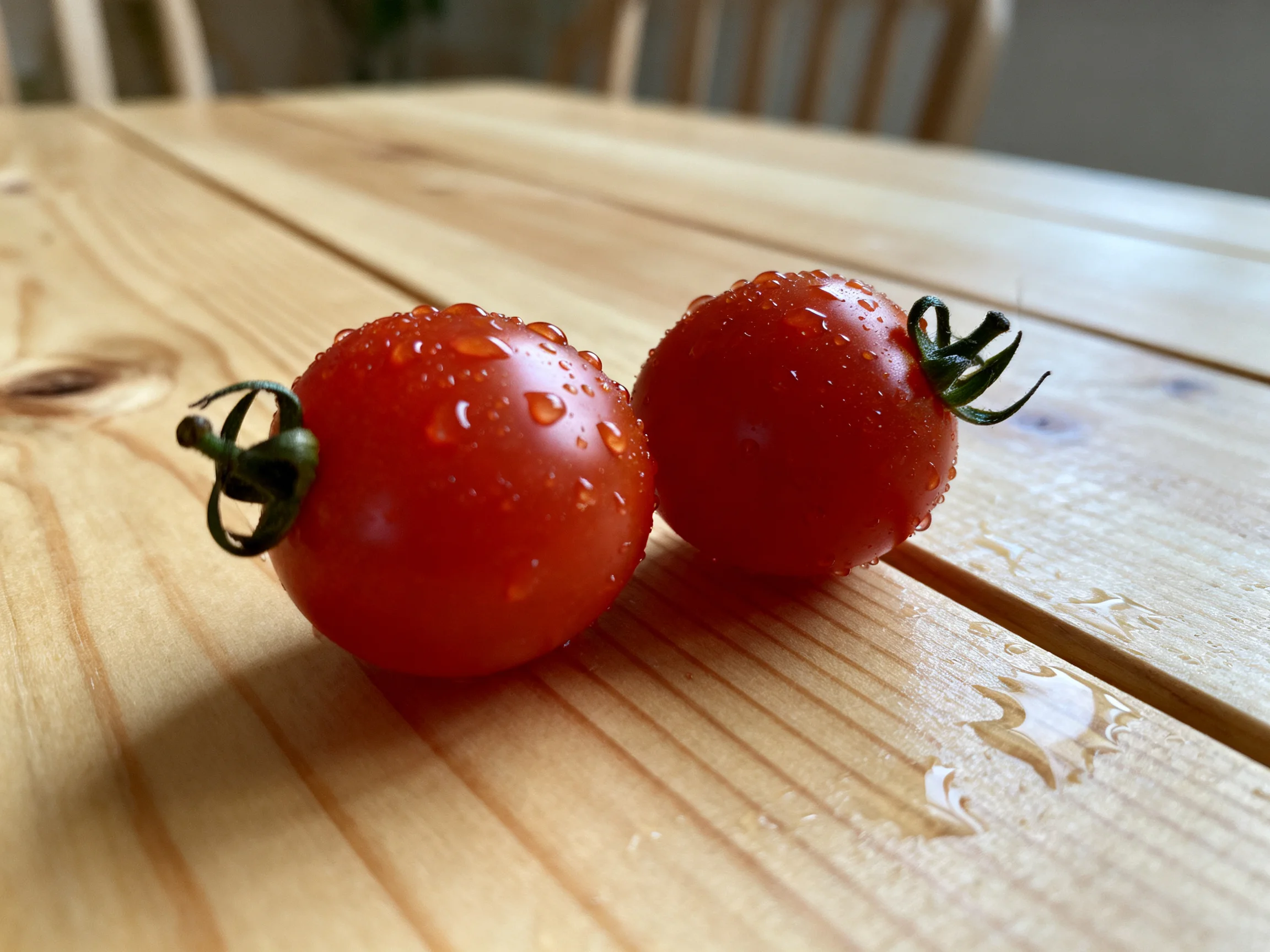 Two vibrant cherry tomatoes with water droplets on a wooden table
