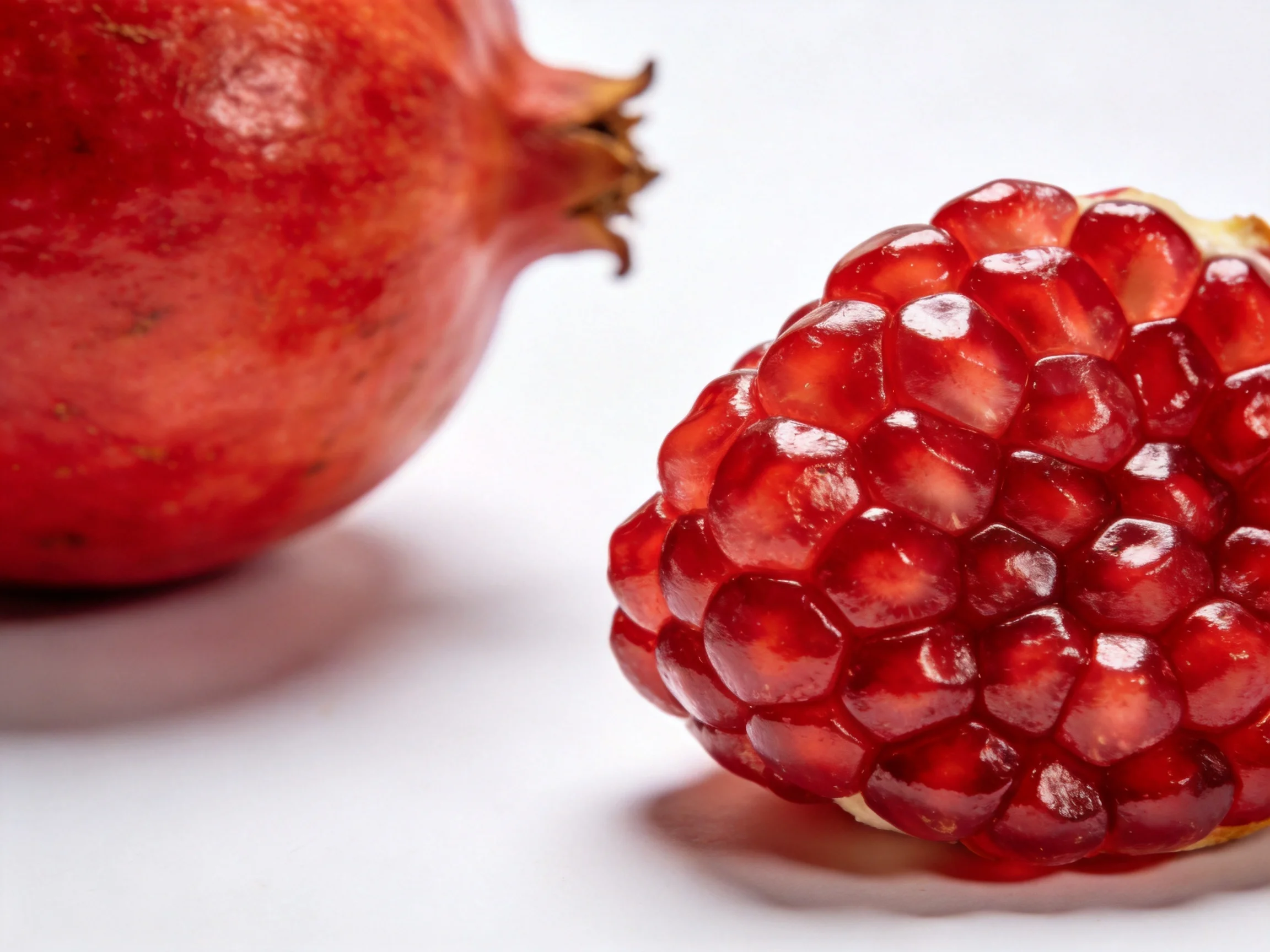 Two vibrant red pomegranates, one whole and one cut open