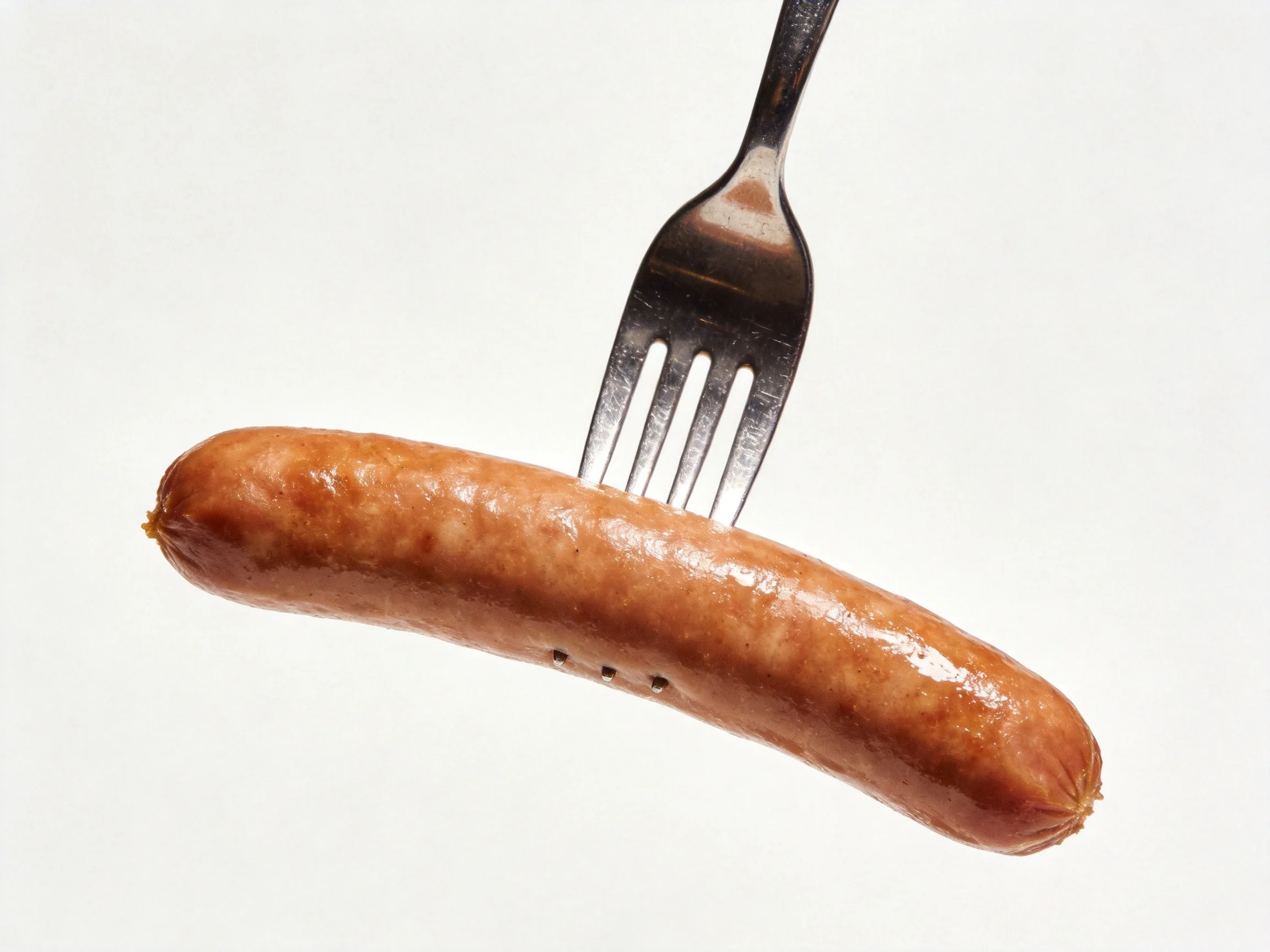 A cooked sausage is pierced by a fork on a white background.