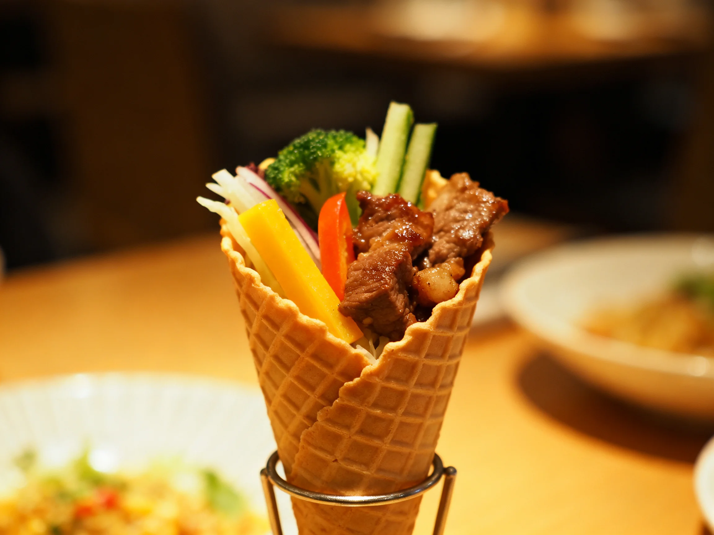 A waffle cone filled with grilled meat and assorted vegetables