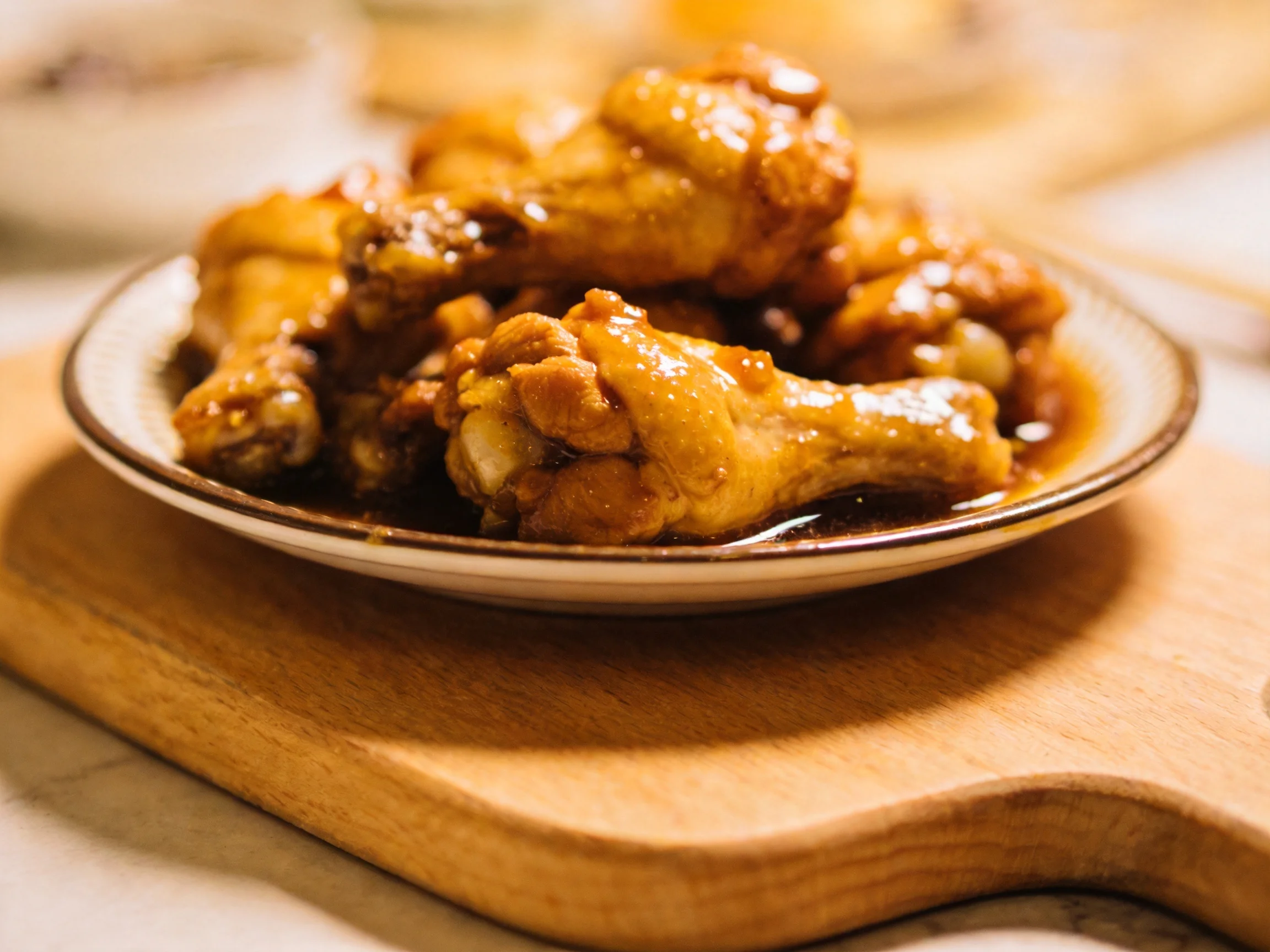 Golden-brown glazed chicken wings served on a ceramic plate