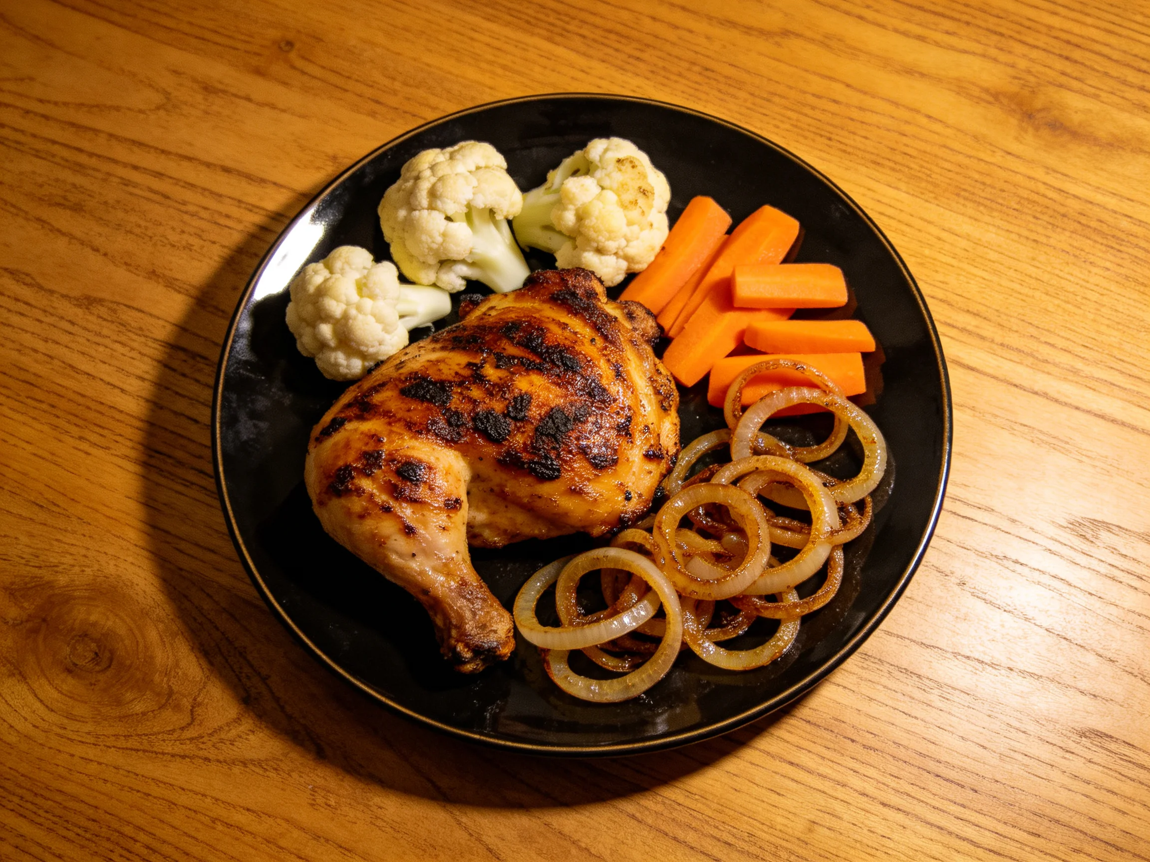 Grilled chicken thigh with cauliflower, carrot sticks, and caramelized onion rings