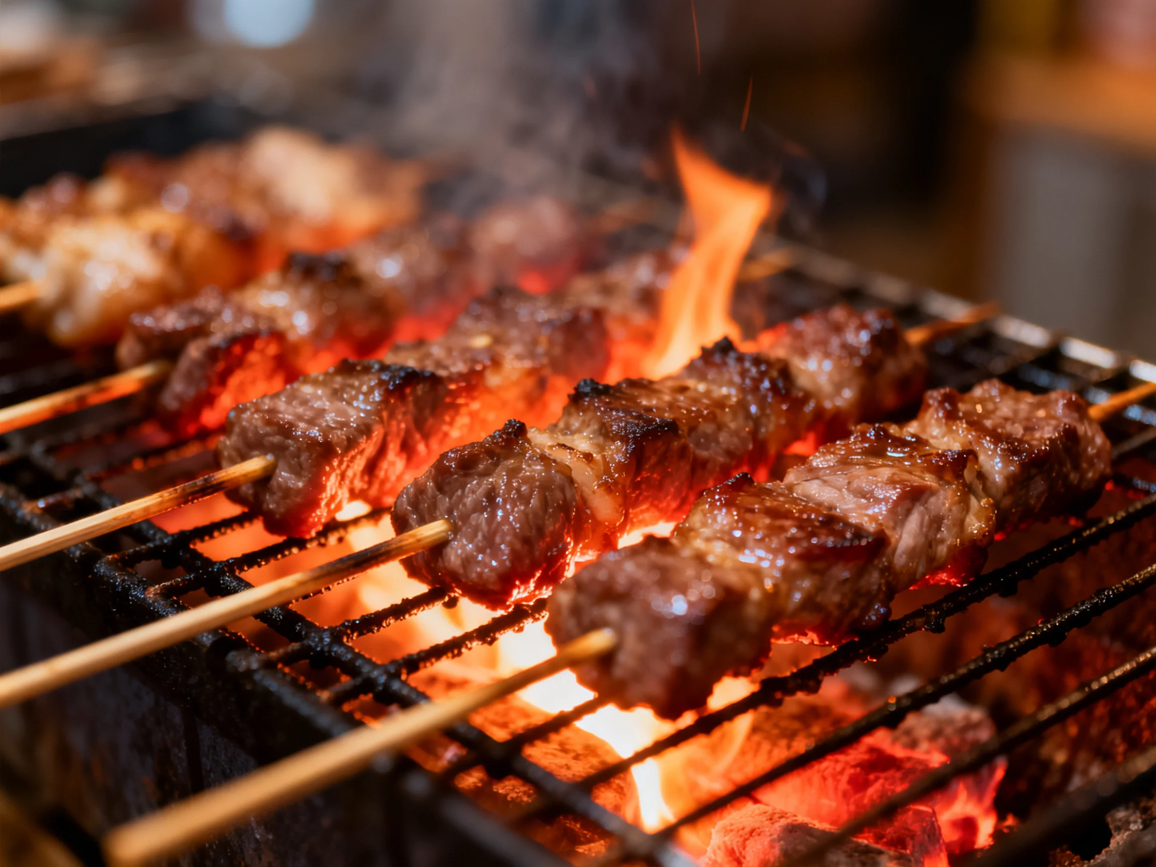 Skewers of grilled meat cook over flames on a charcoal grill.