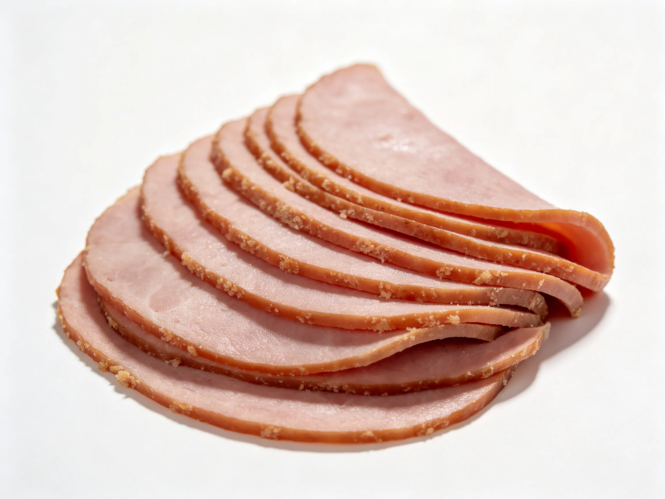 Thinly sliced ham arranged in curved fan formation with browned edges