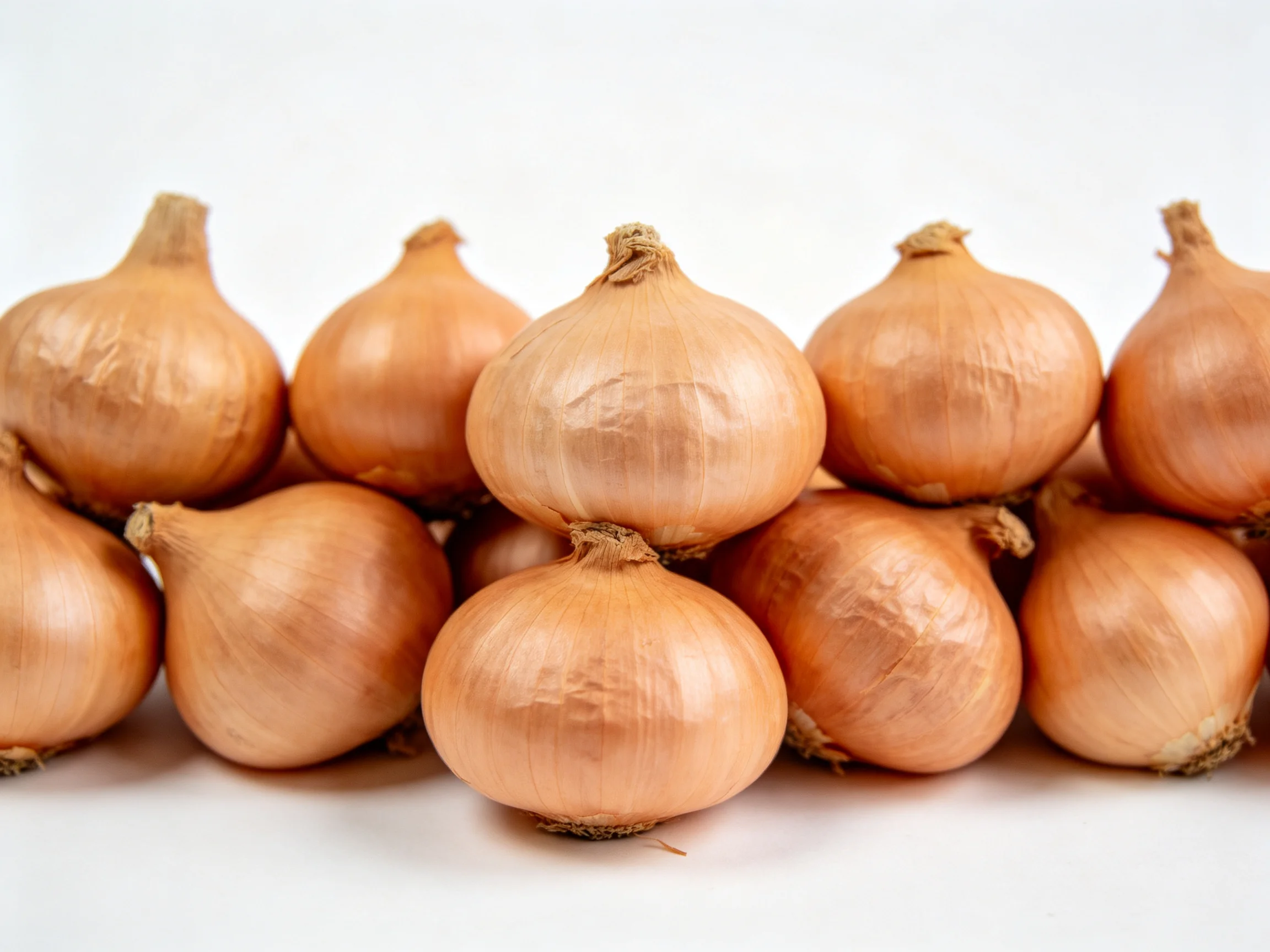 A cluster of golden-brown onions arranged in tight, compact piles