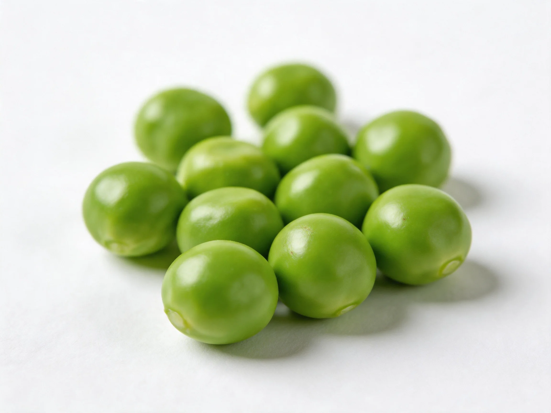 A cluster of vibrant green peas scattered on a plain white background