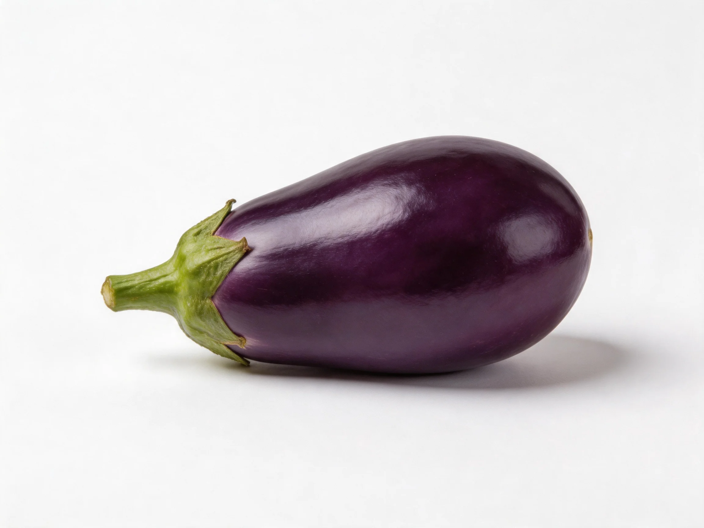 A glossy purple eggplant with a green stem against a plain white backdrop