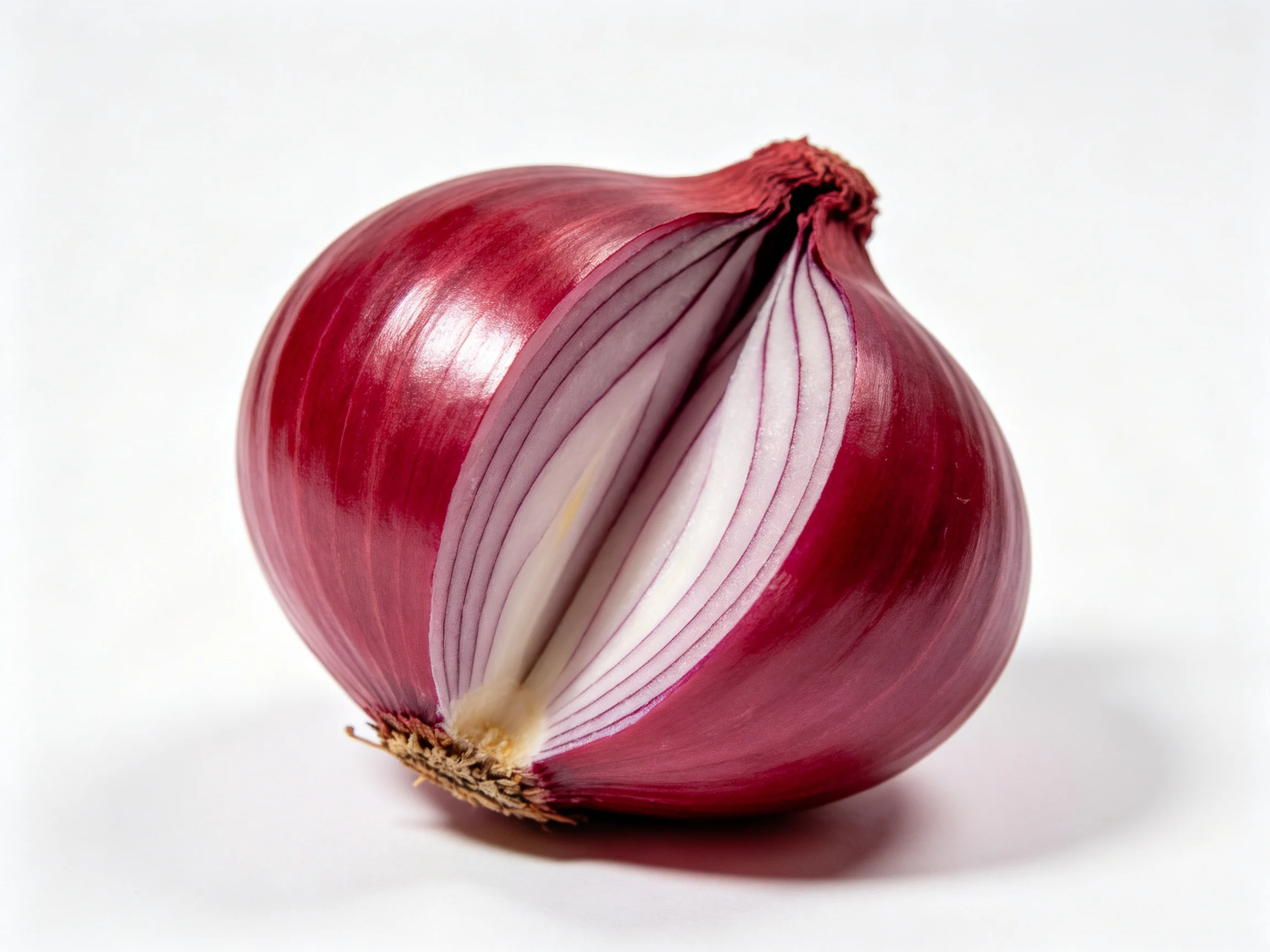 A halved red onion with layered purple and white interiors