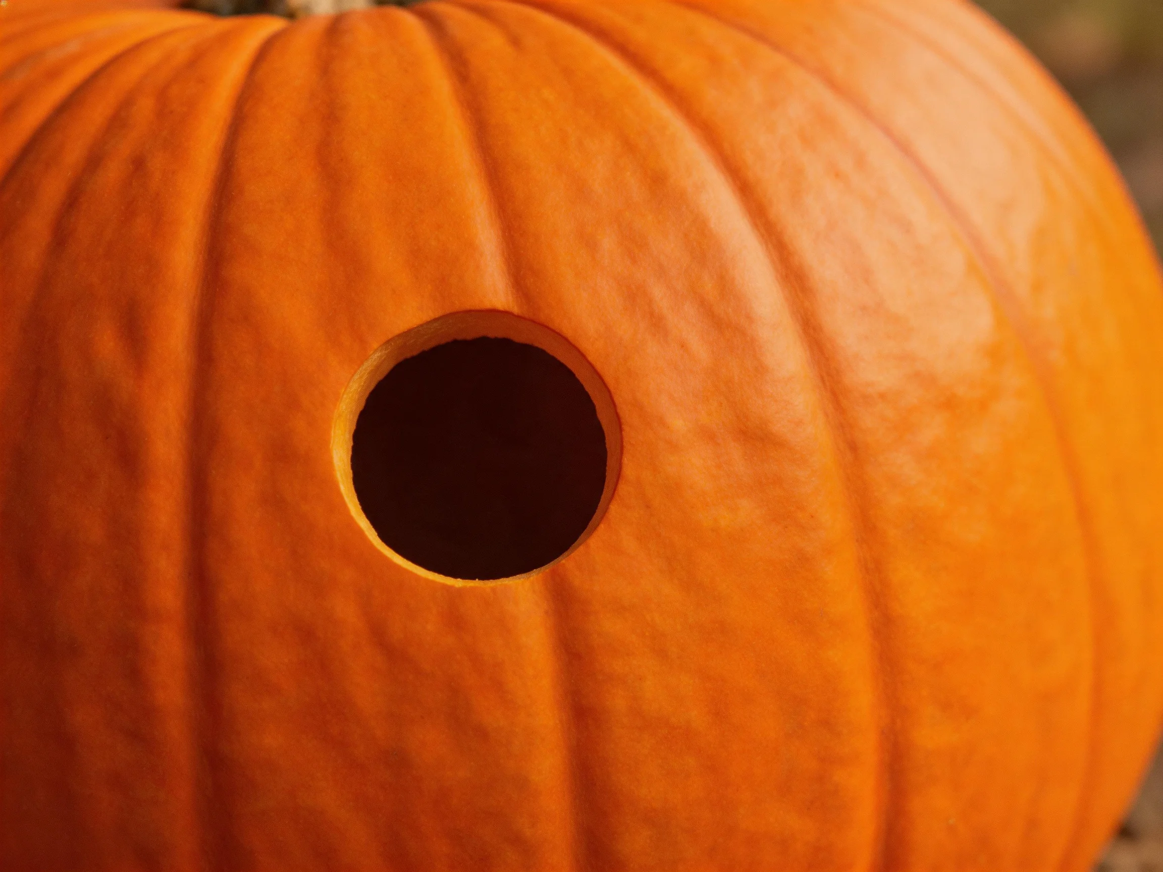 A large orange pumpkin with a single circular opening