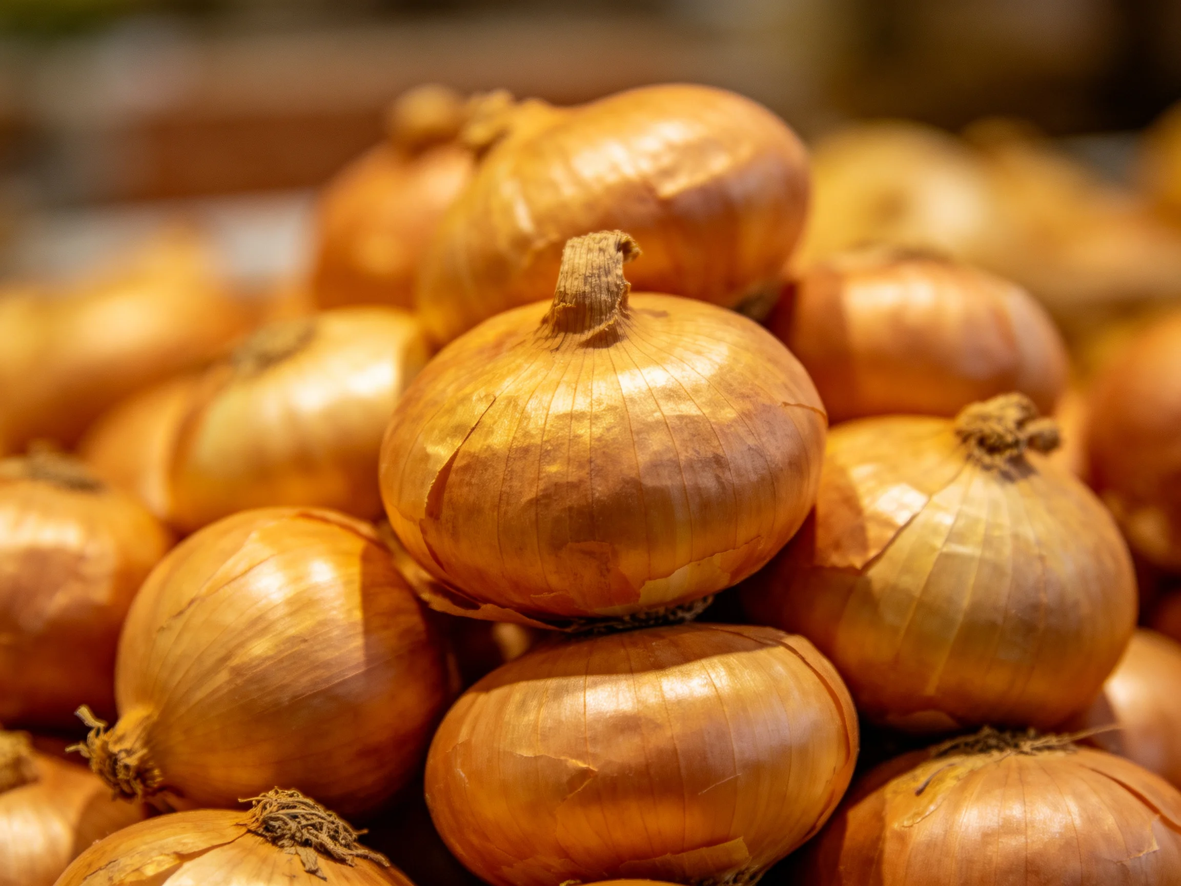 A large pile of golden-brown onions stacked closely together
