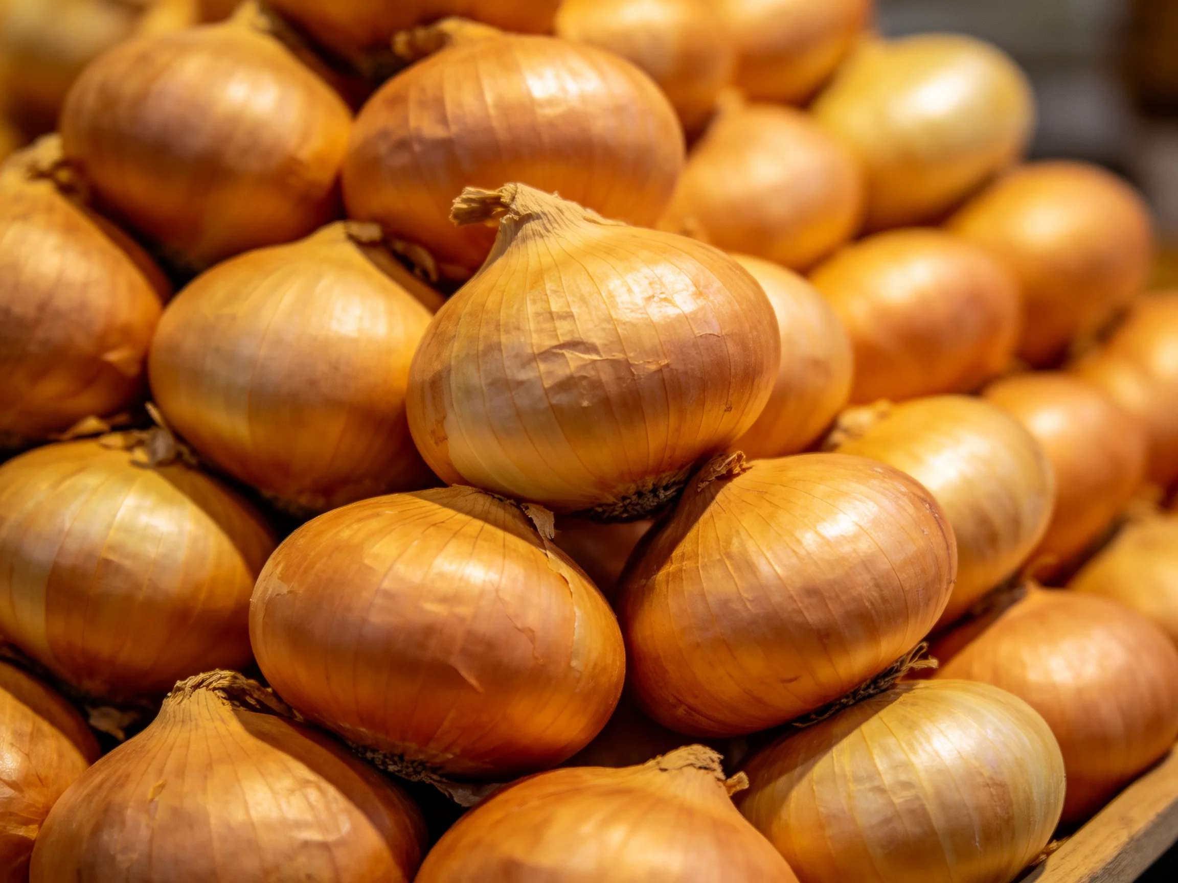 A large stack of golden-brown onions piled densely together