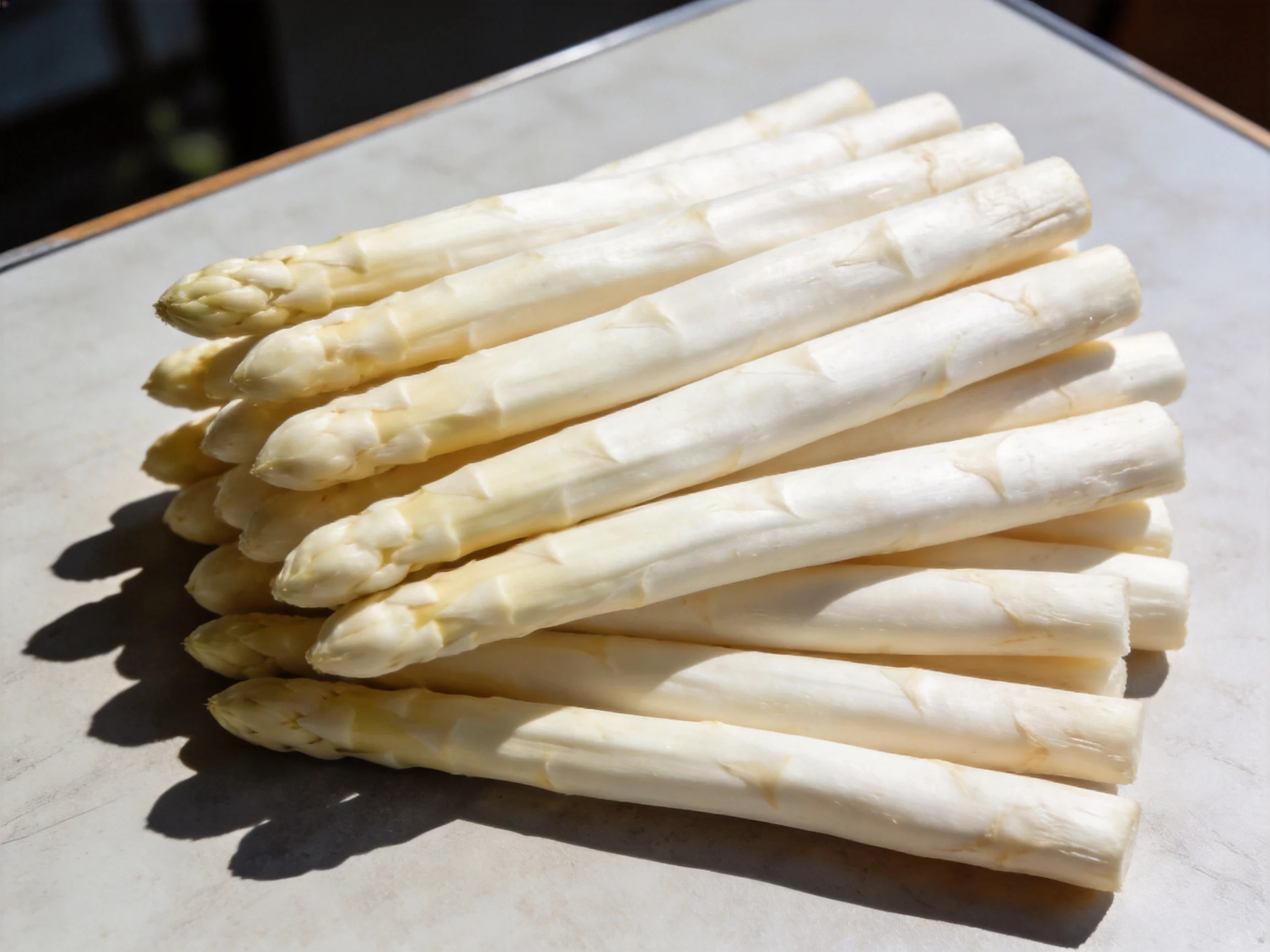 A pile of fresh white asparagus spears arranged on a light surface
