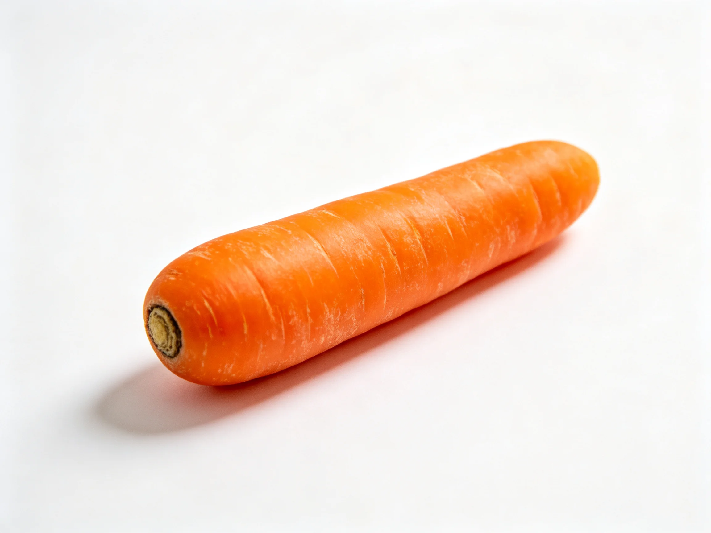 A single vivid orange carrot resting on a stark white backdrop
