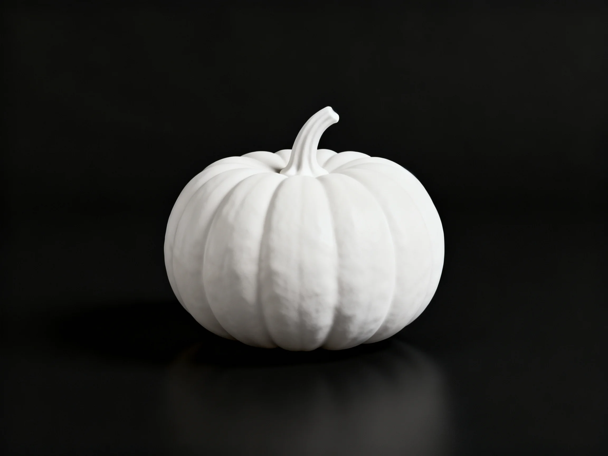 A single white ribbed pumpkin centered on a black surface