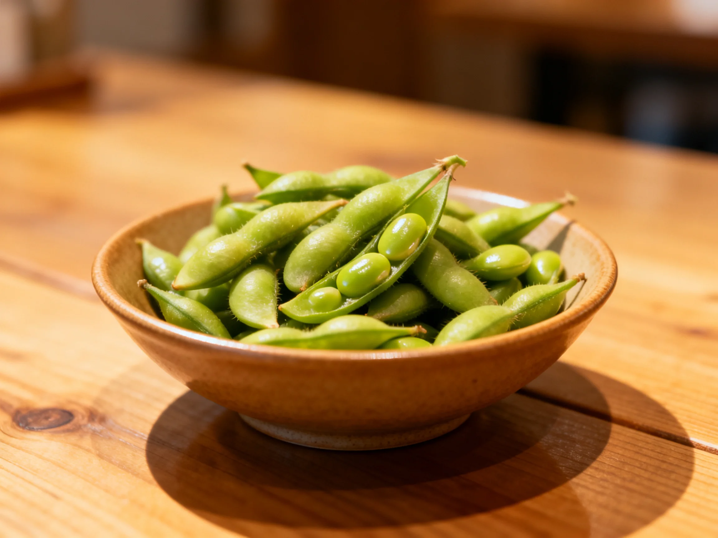 A small brown bowl holding numerous fresh green edamame pods