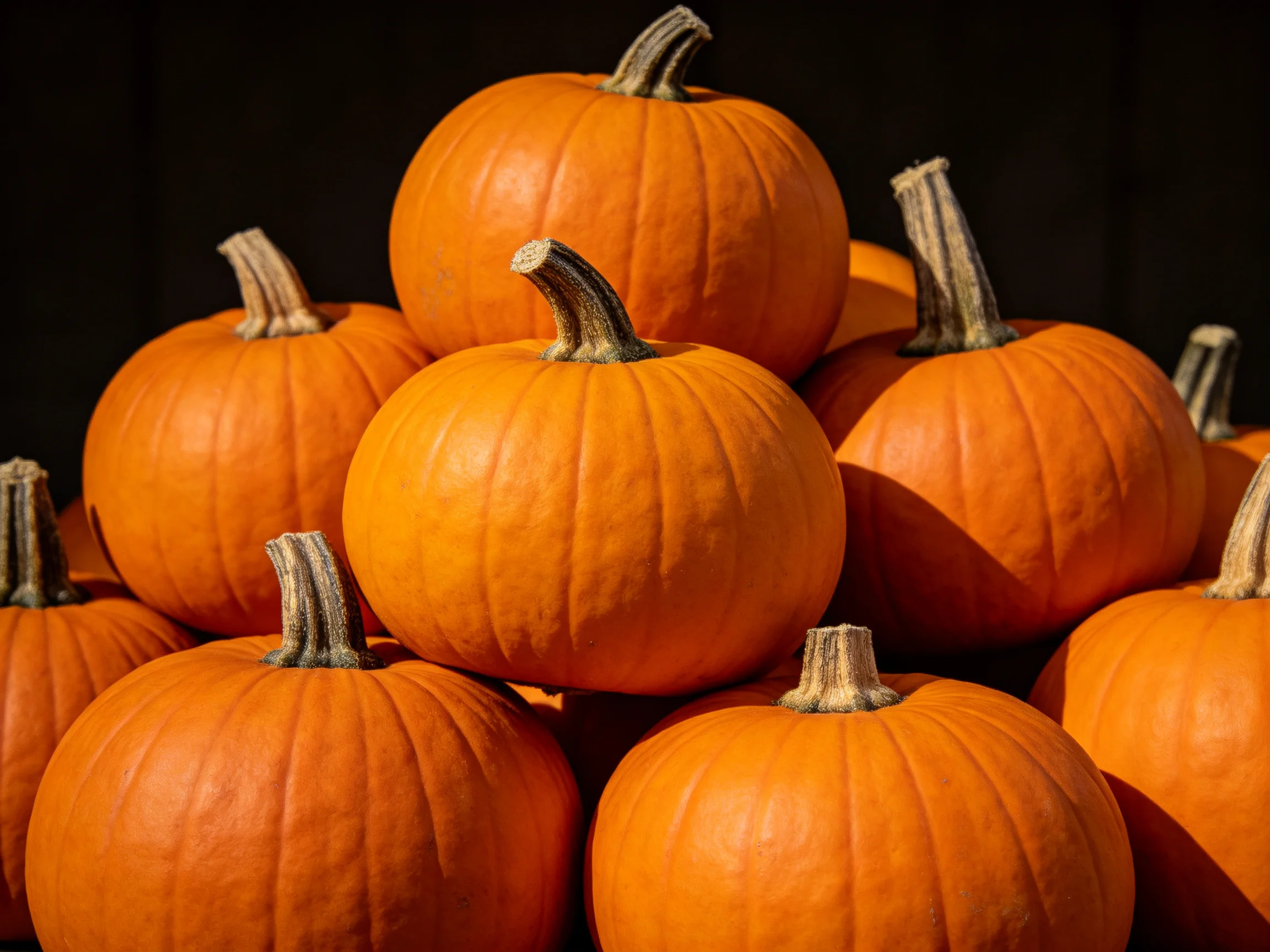 A stack of vibrant orange pumpkins arranged in a pyramid