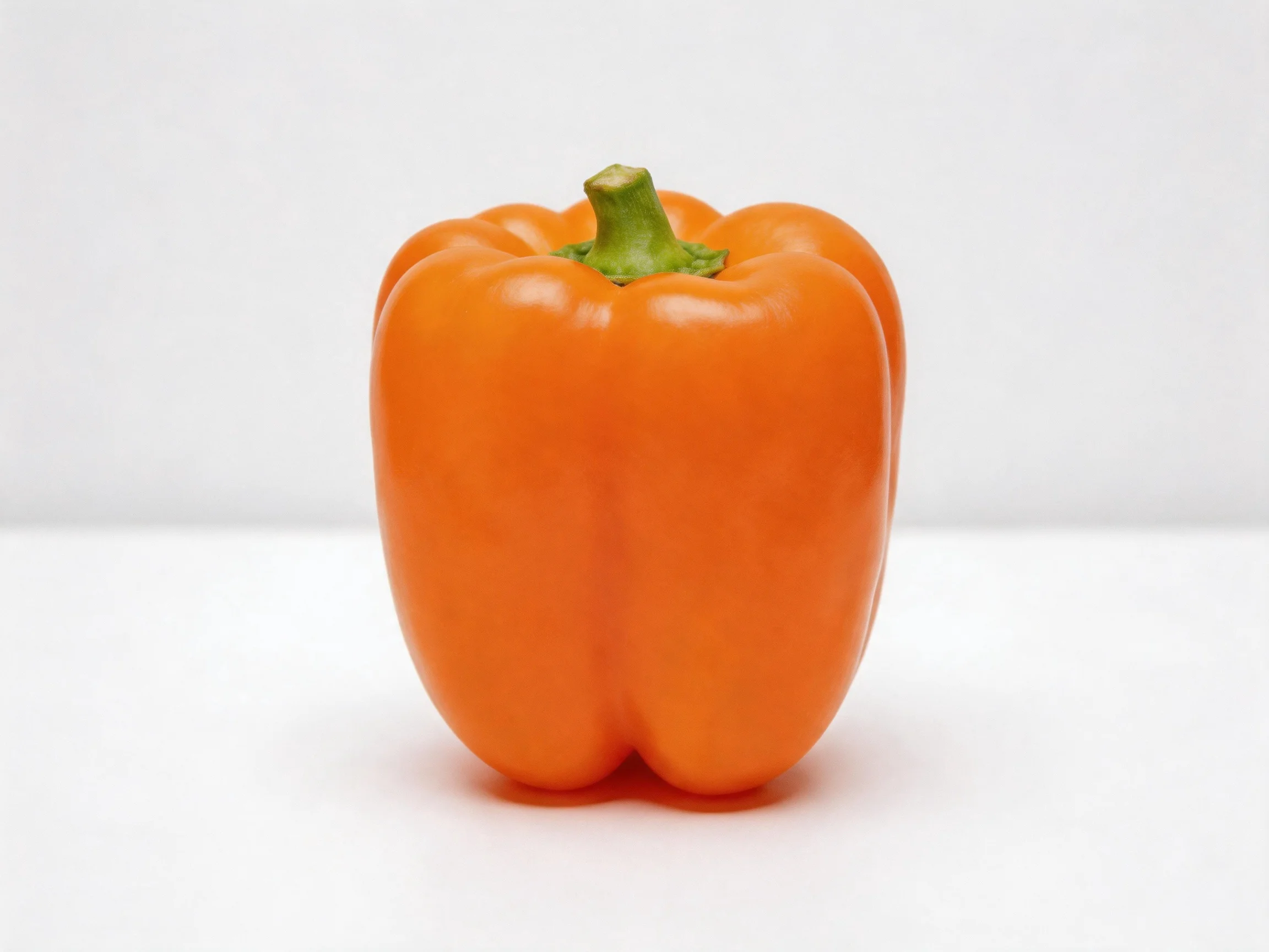 A vibrant orange bell pepper centered on a white surface