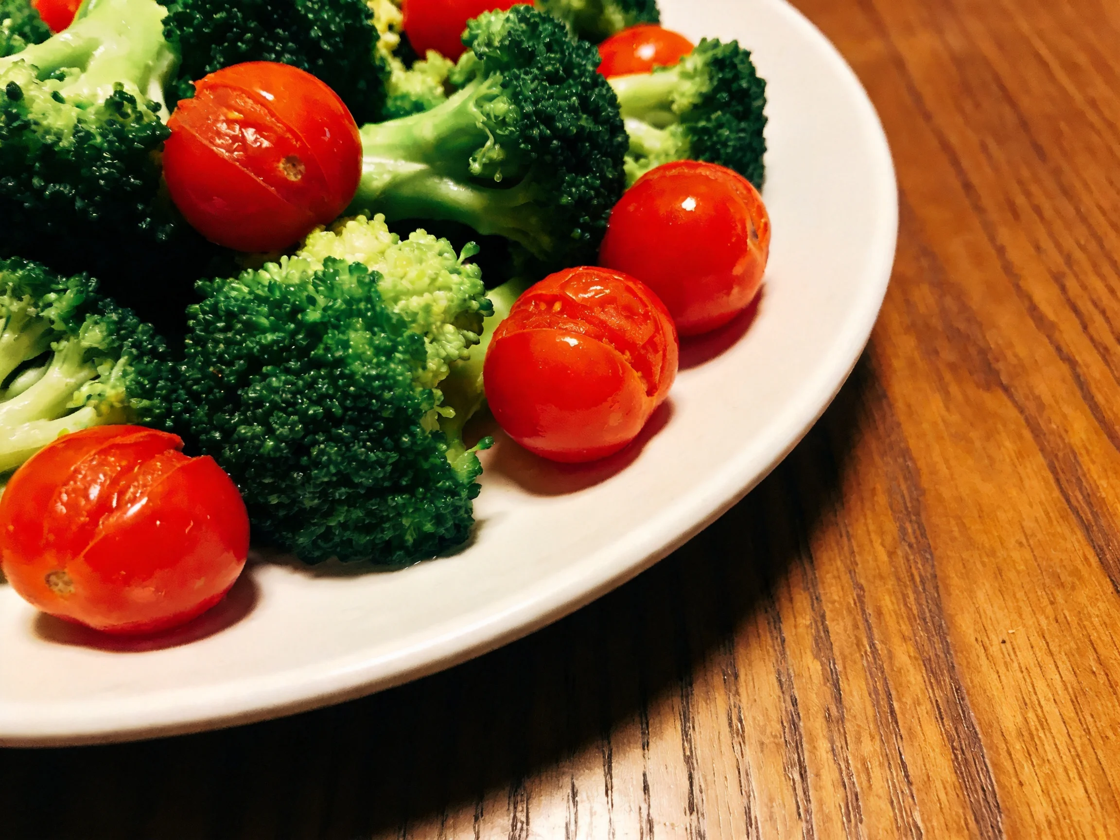 Cherry tomatoes and steamed broccoli on a white plate