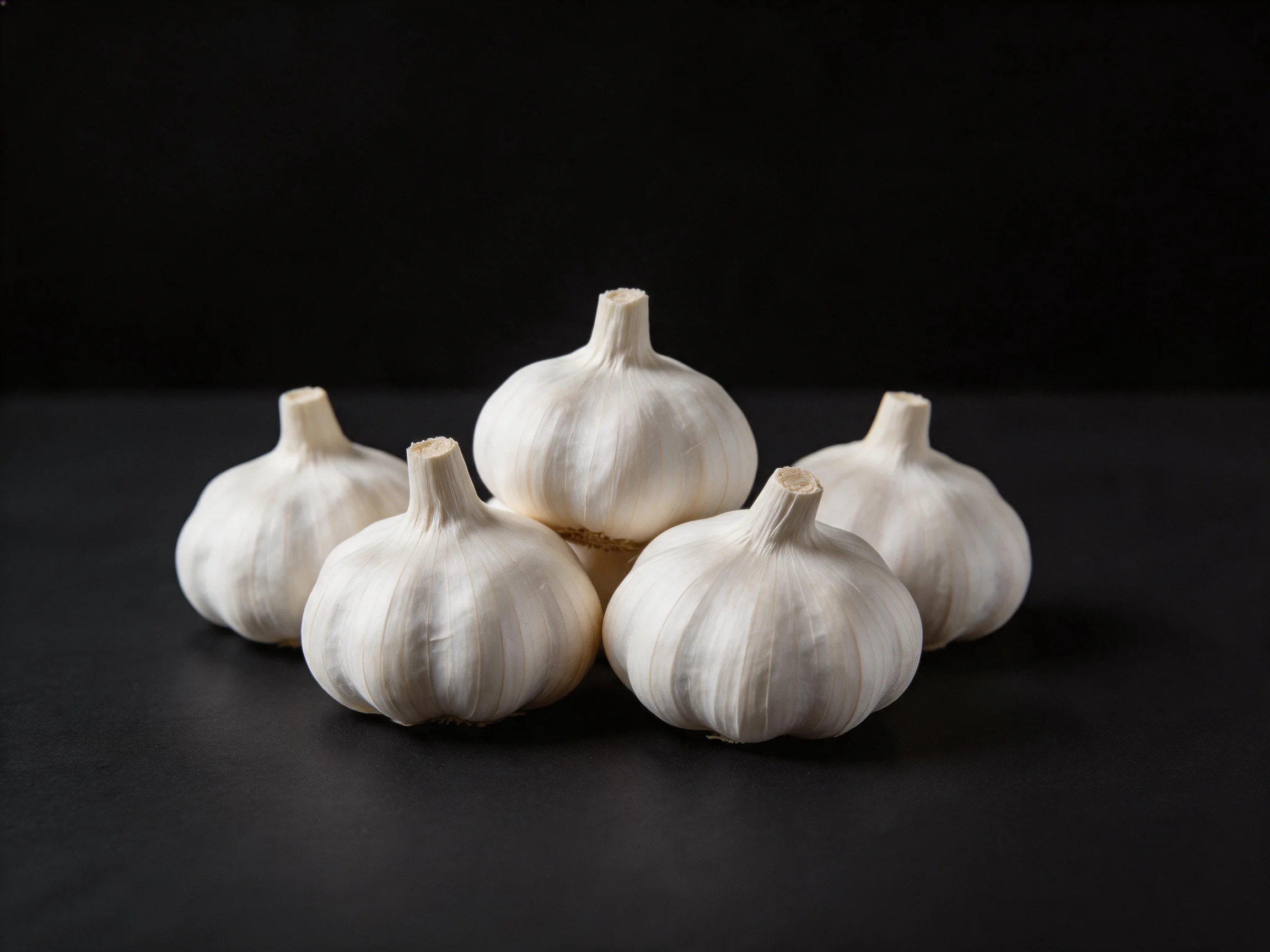 Five fresh garlic bulbs arranged closely against a black backdrop
