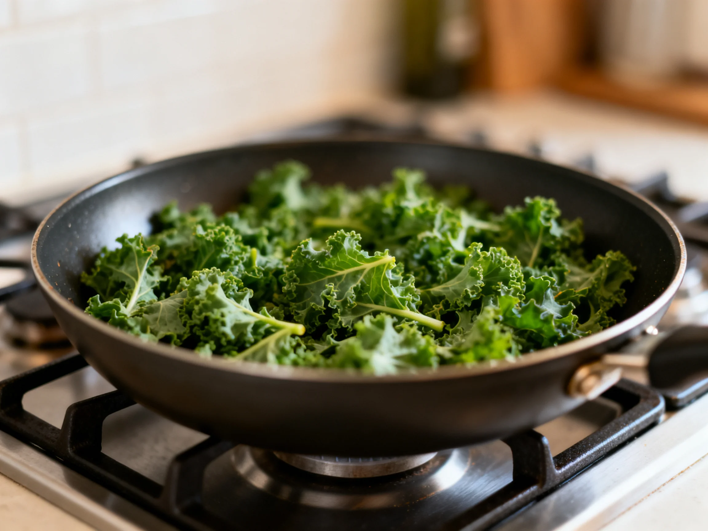Fresh curly kale cooking in a black skillet on a gas stove