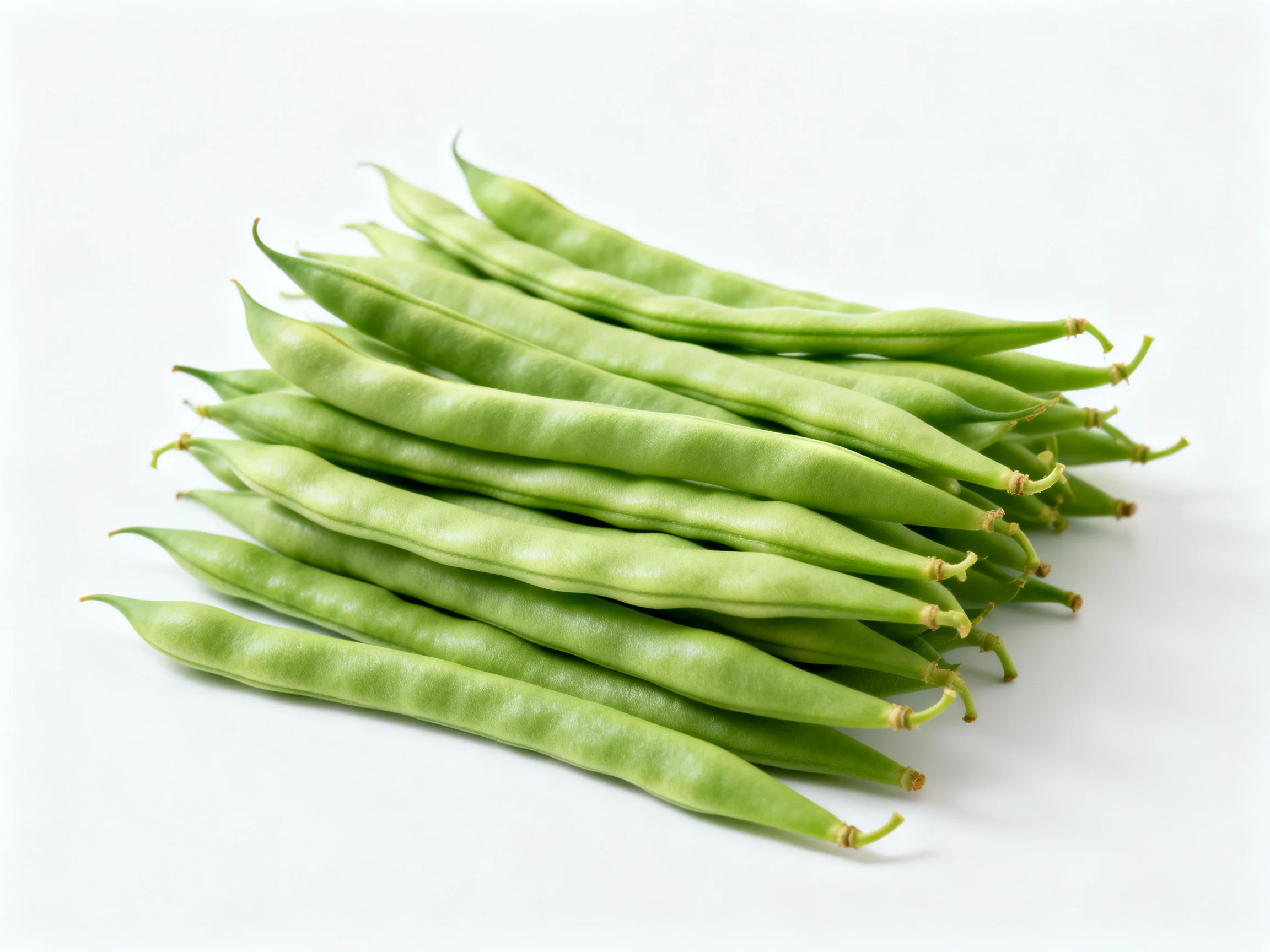 Fresh green bean pods stacked neatly on a plain white surface