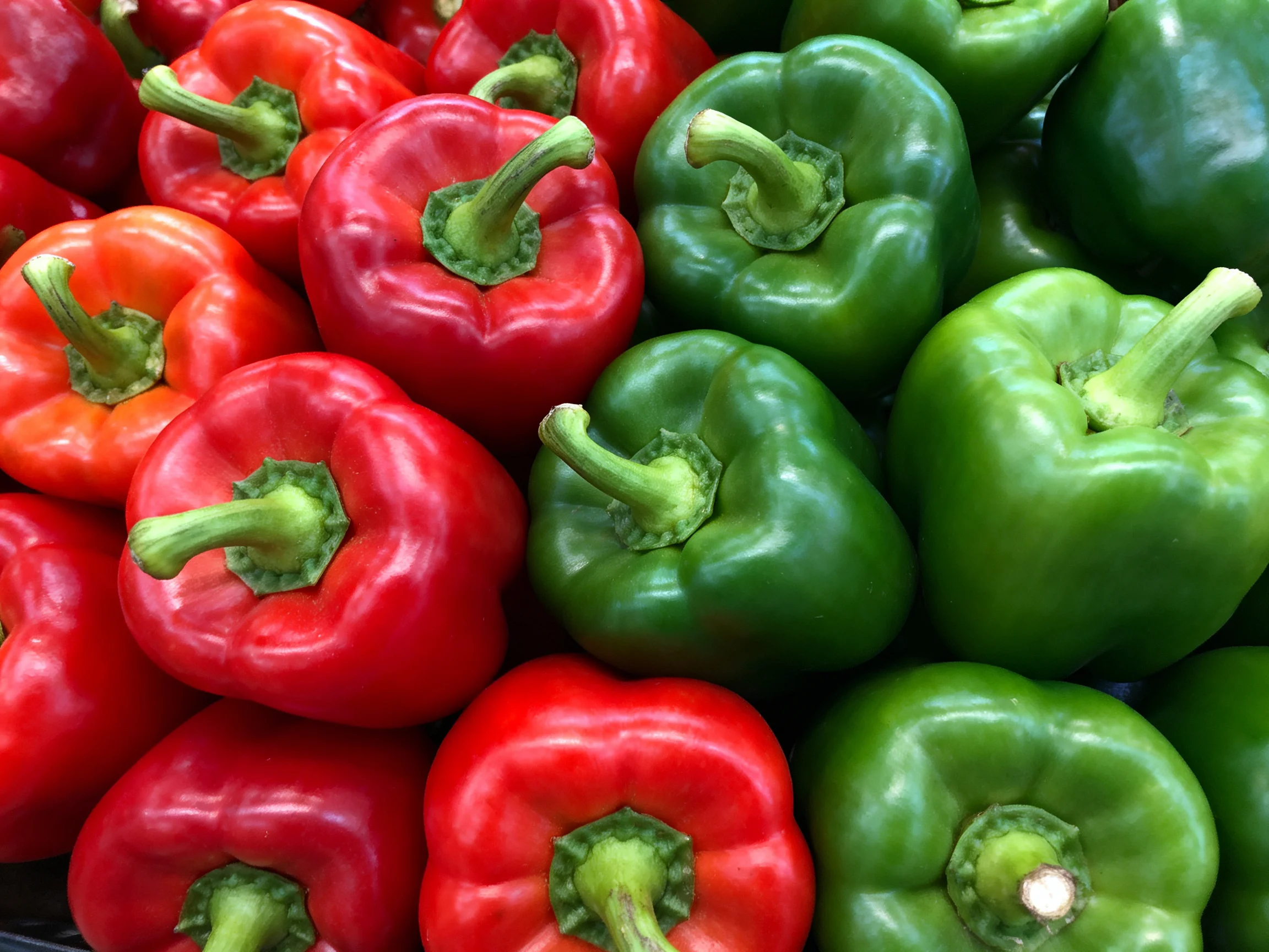 Fresh red and green bell peppers arranged closely together
