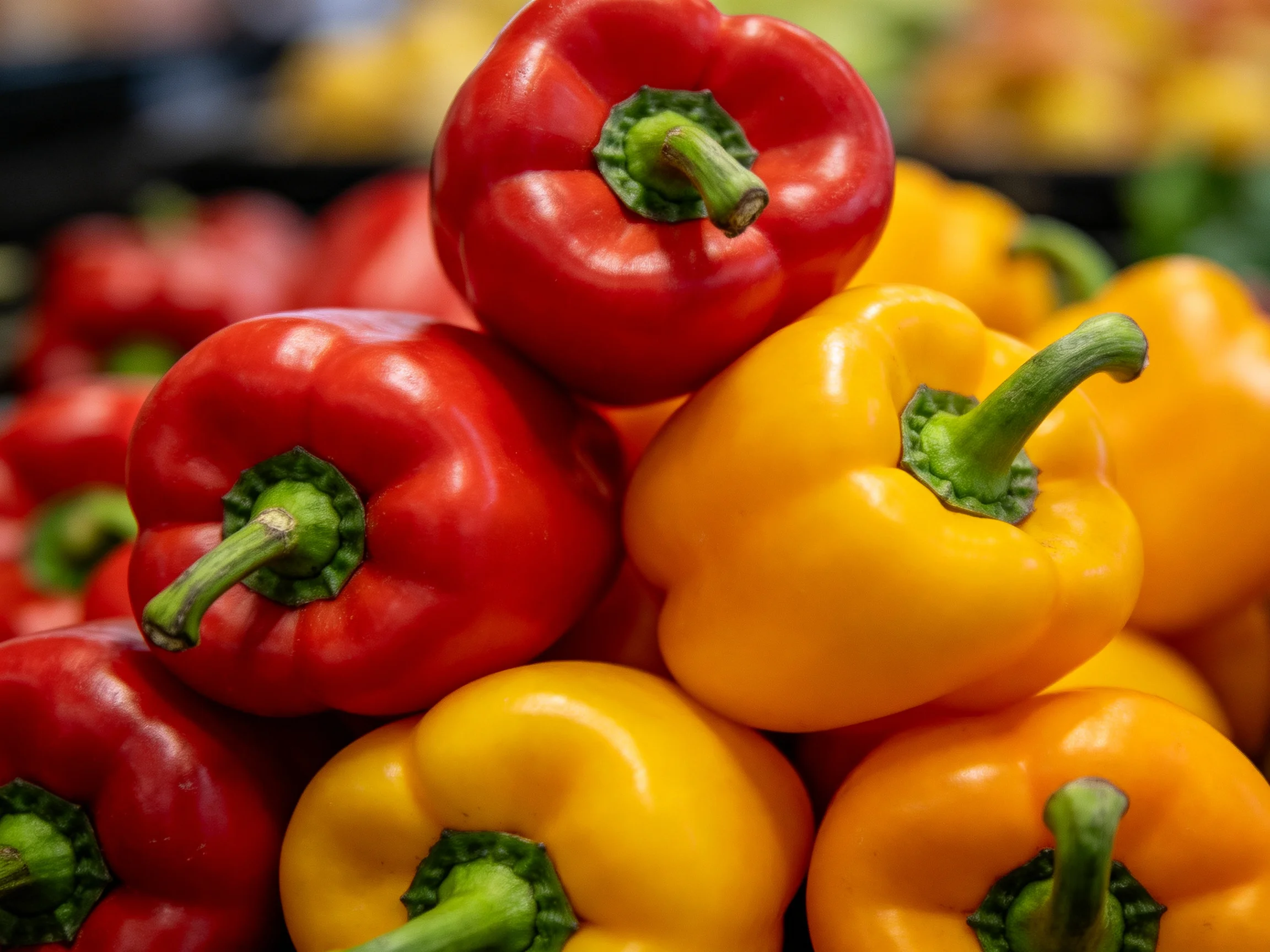 Fresh red and yellow bell peppers stacked in a market display