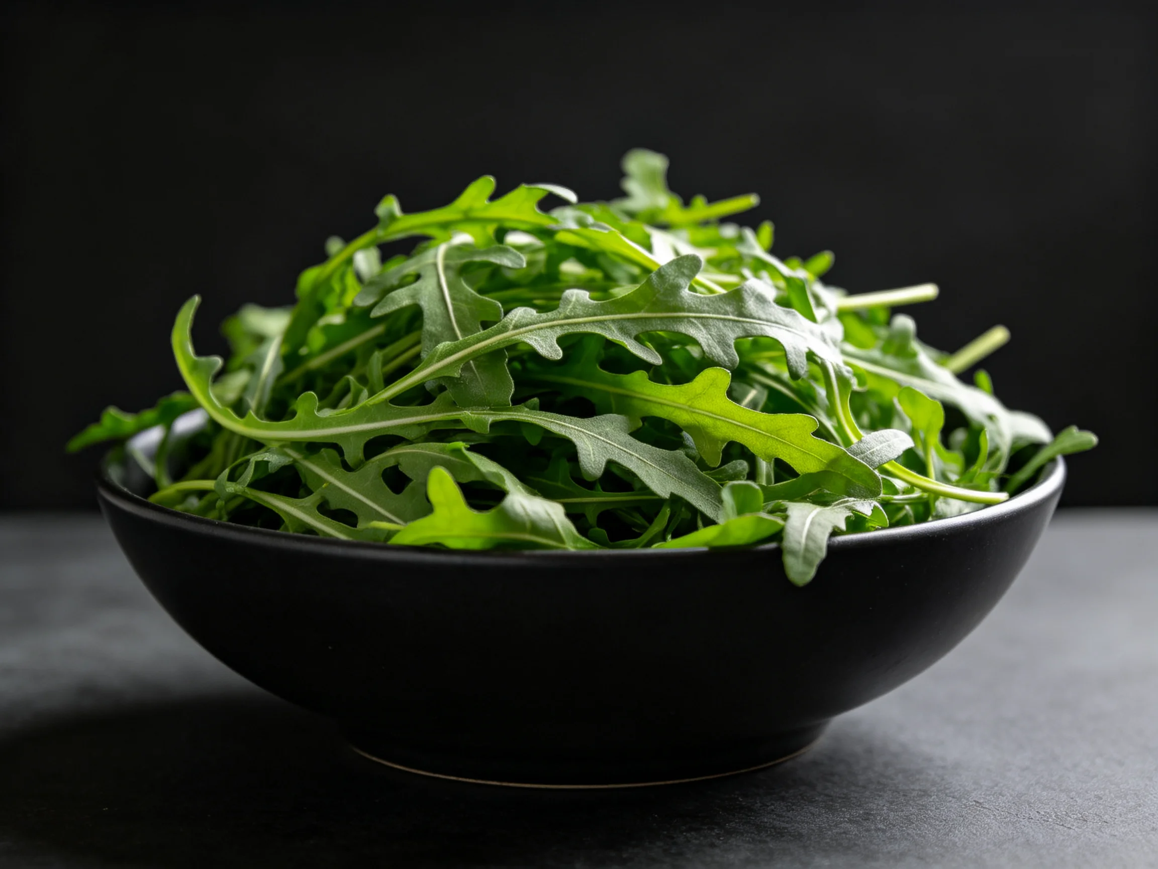 Fresh vibrant arugula greens arranged in a glossy black bowl