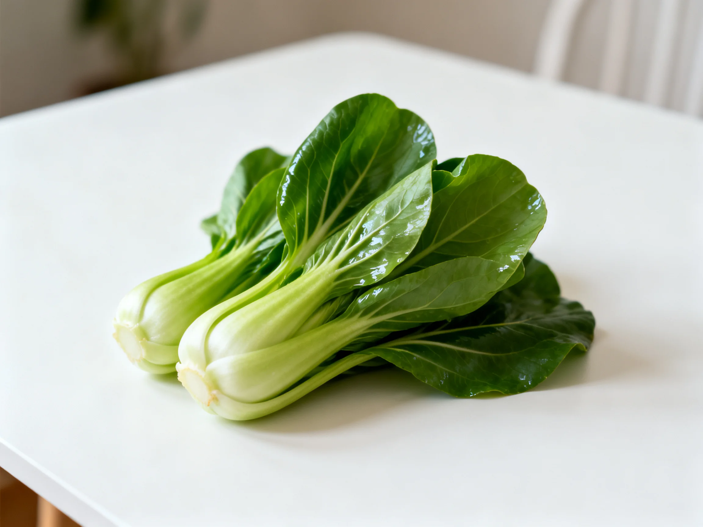 Fresh vibrant green bok choy arranged on a smooth white table