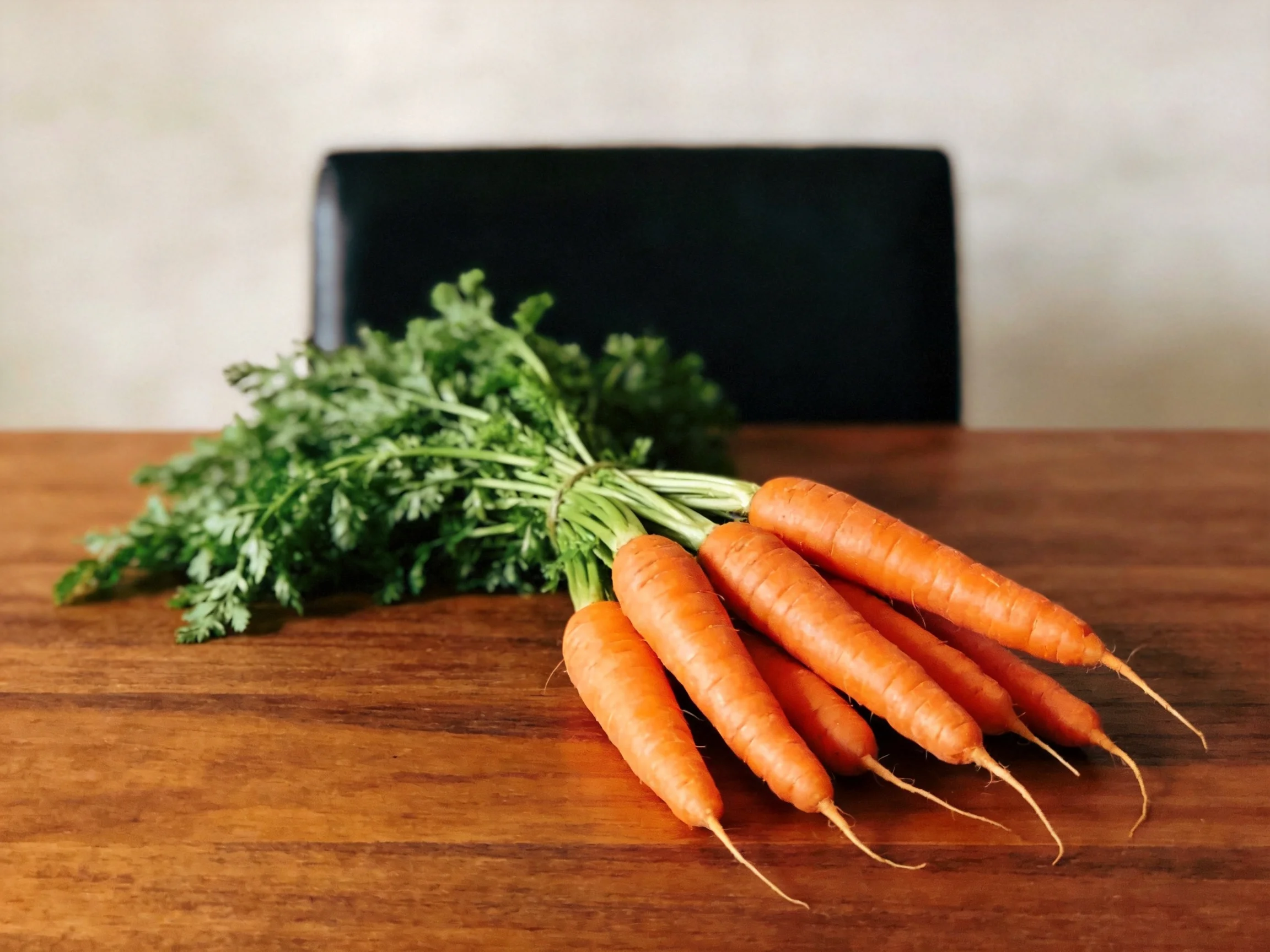 Freshly harvested carrots with green tops on a wooden table