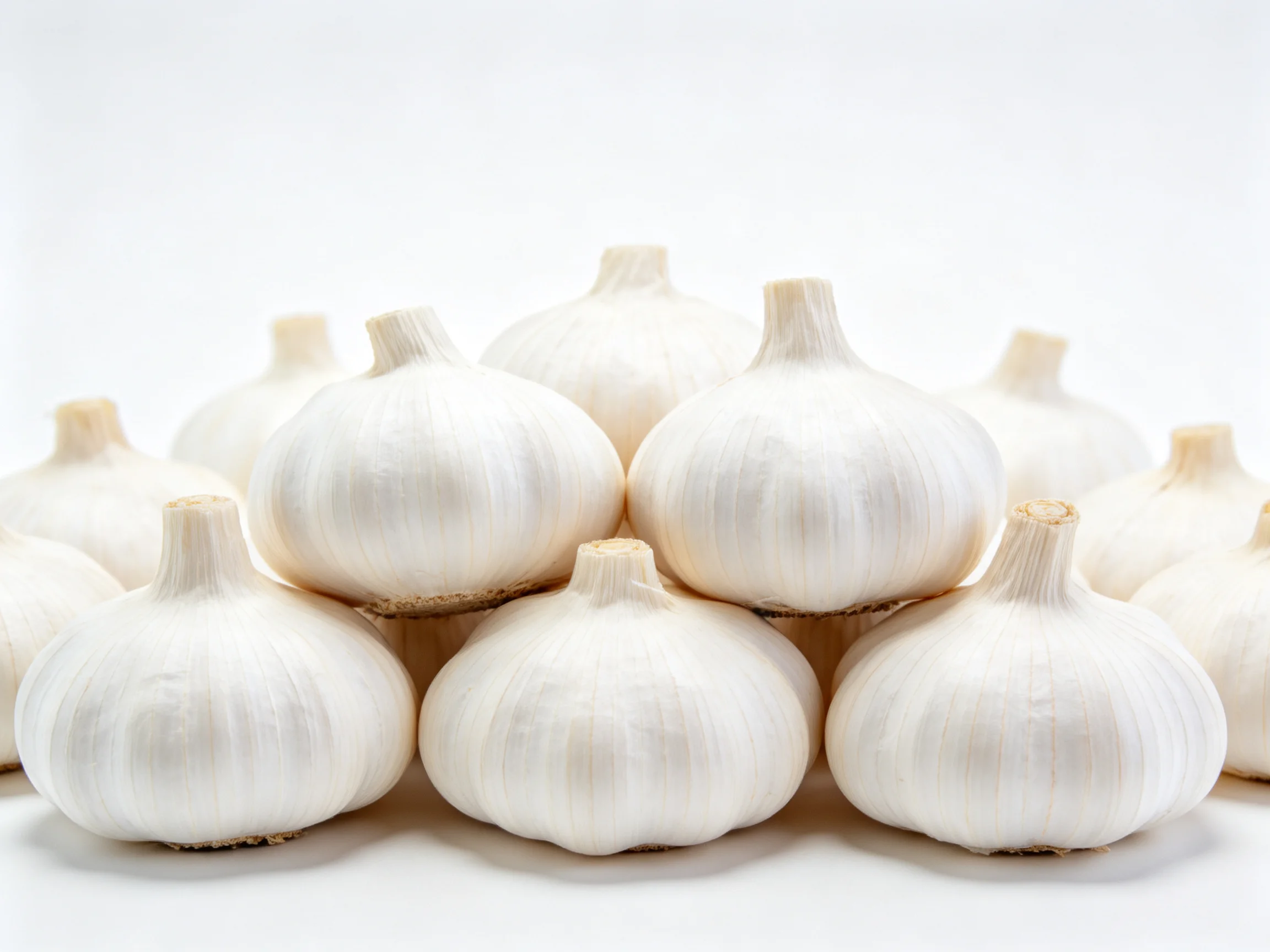Freshly harvested garlic bulbs arranged in a pyramid formation with smooth white skins