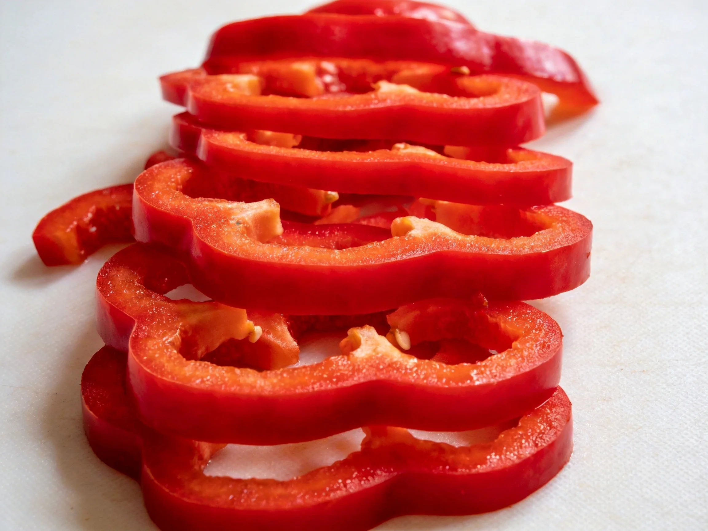 Freshly sliced vibrant red bell pepper rings arranged vertically