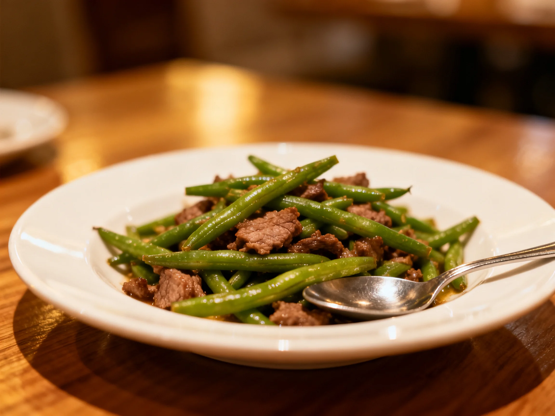 Green beans and beef stir-fry served in a white ceramic bowl