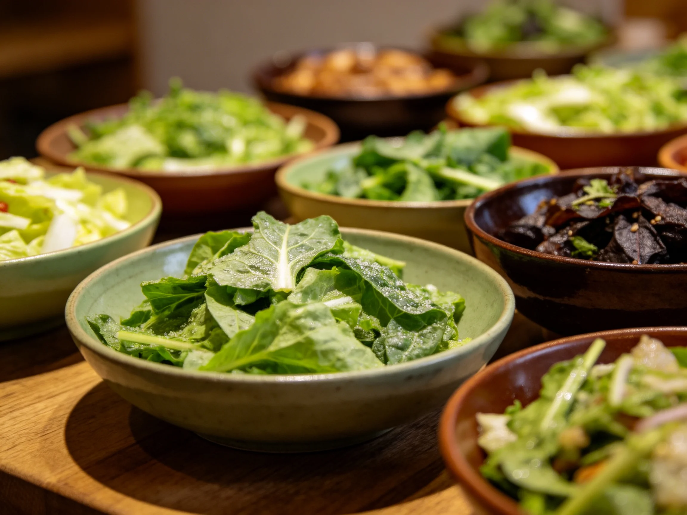 Multiple ceramic bowls filled with fresh green salads and mixed vegetables