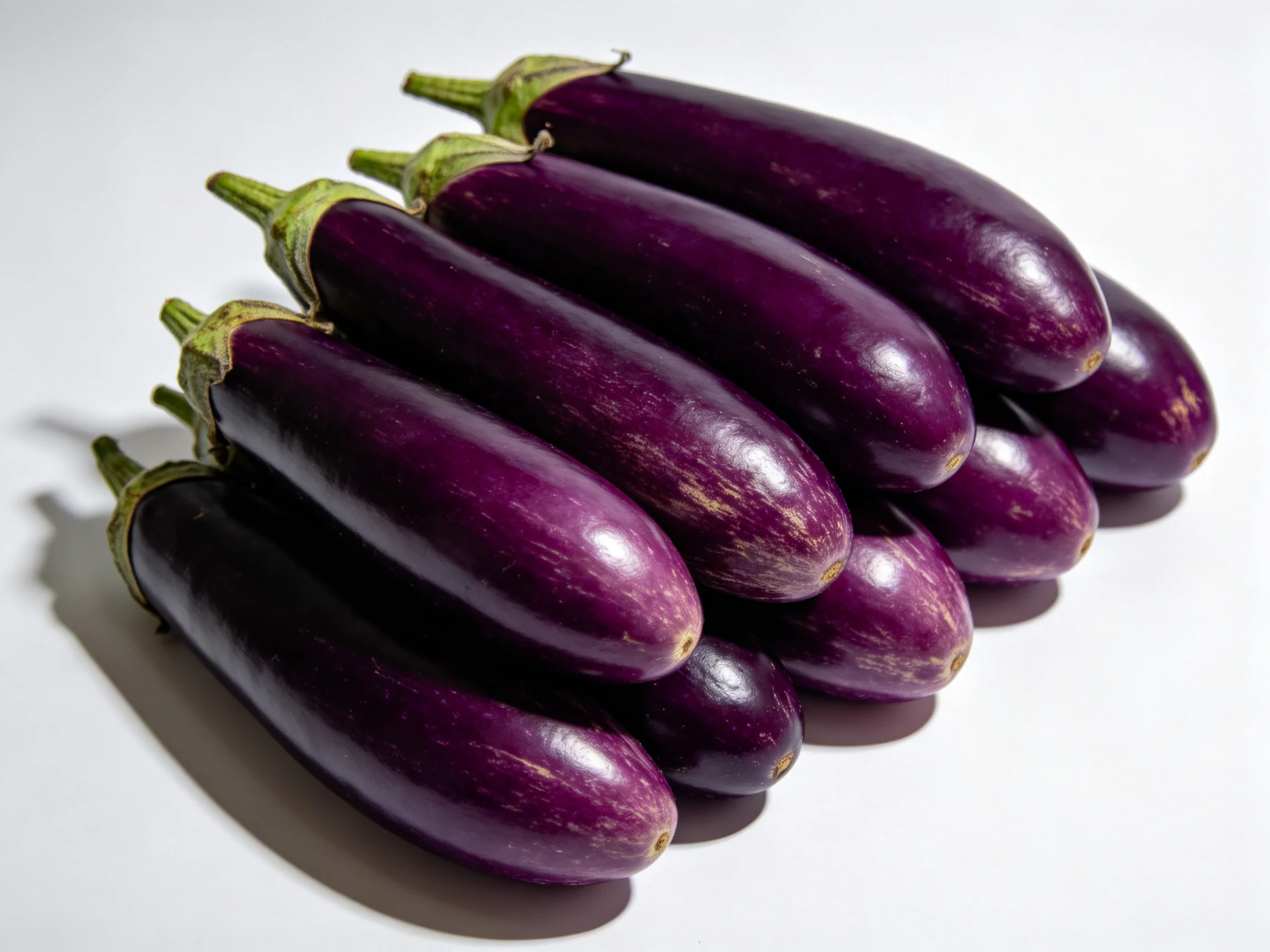 Nine glossy purple eggplants clustered in rows on a white surface