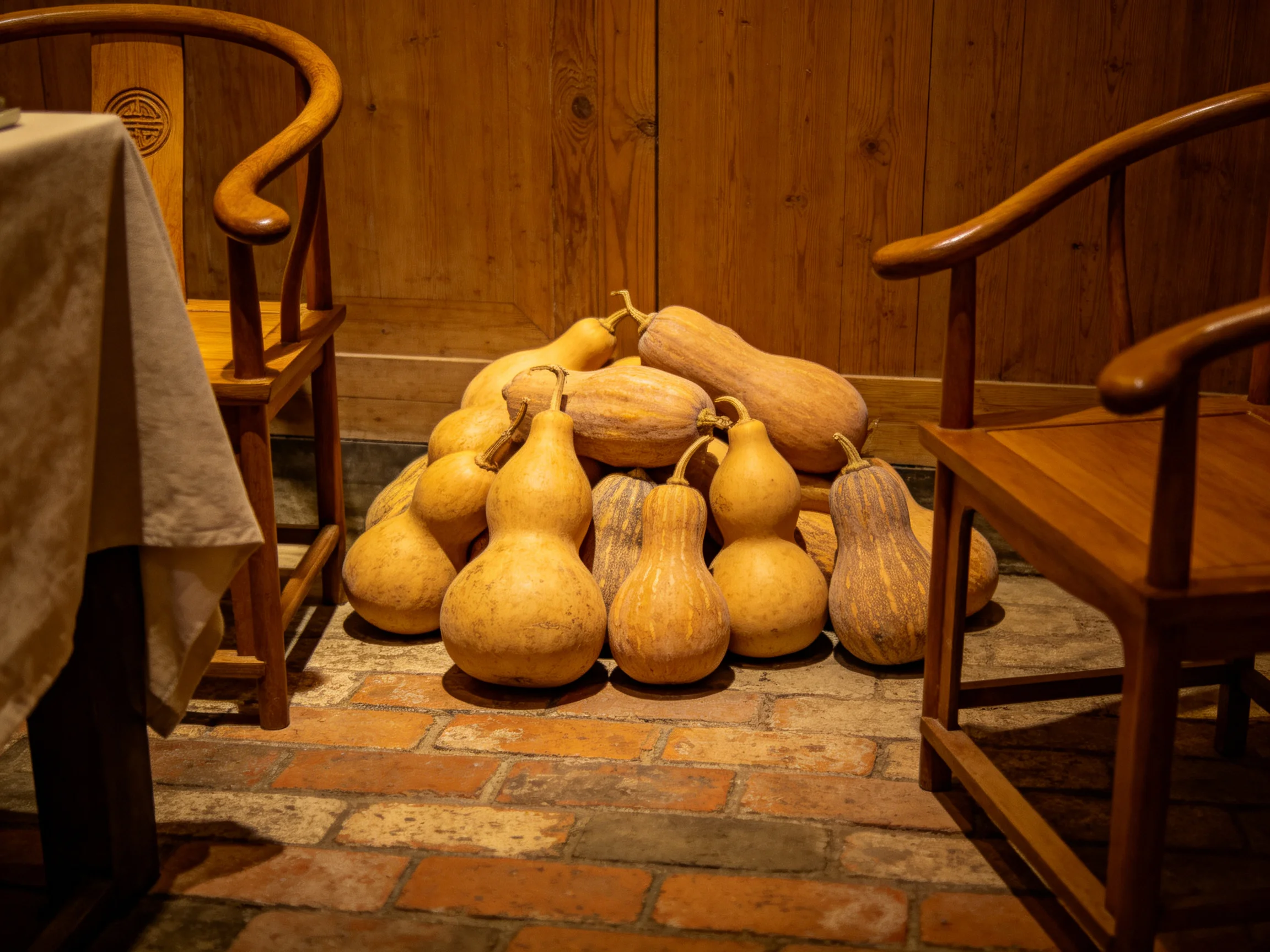 Pile of assorted gourds between wooden chairs in a rustic wooden room