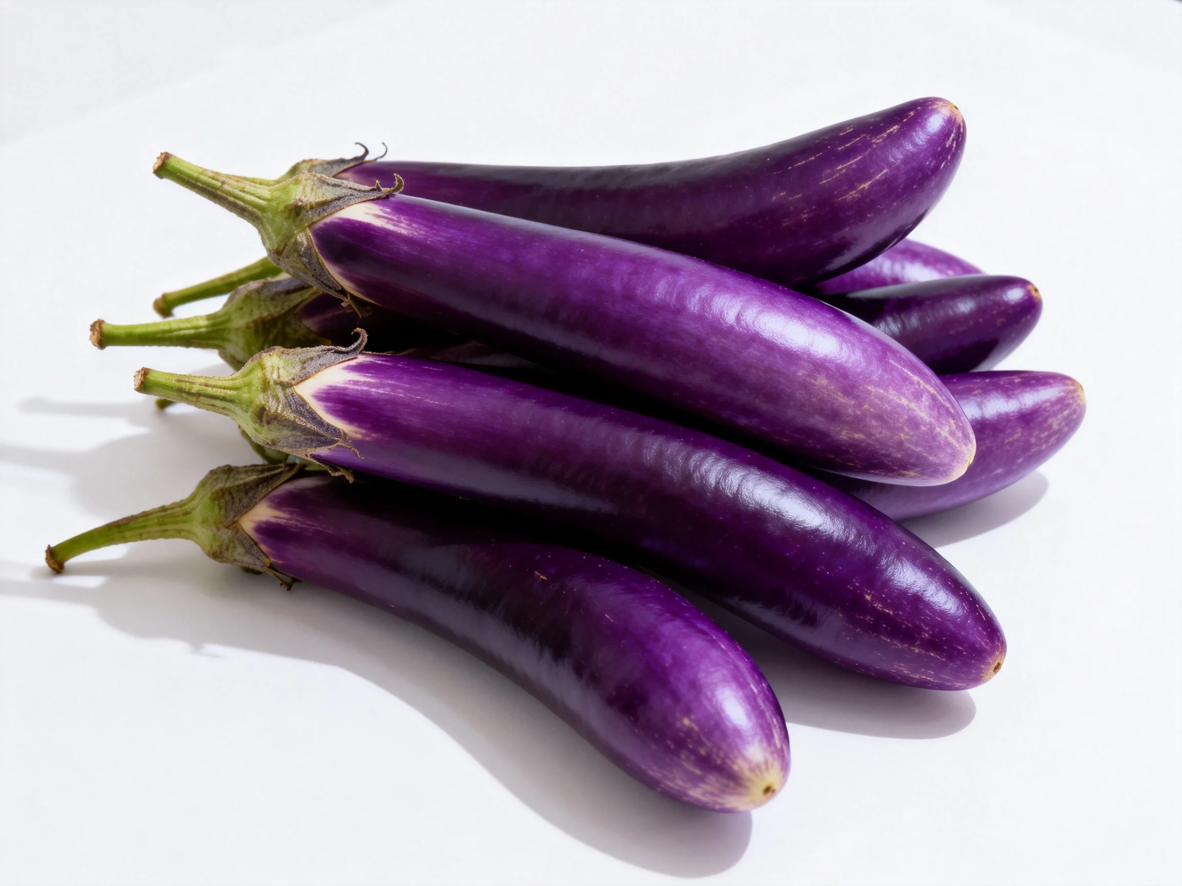 Several vibrant purple elongated eggplants clustered on a white surface