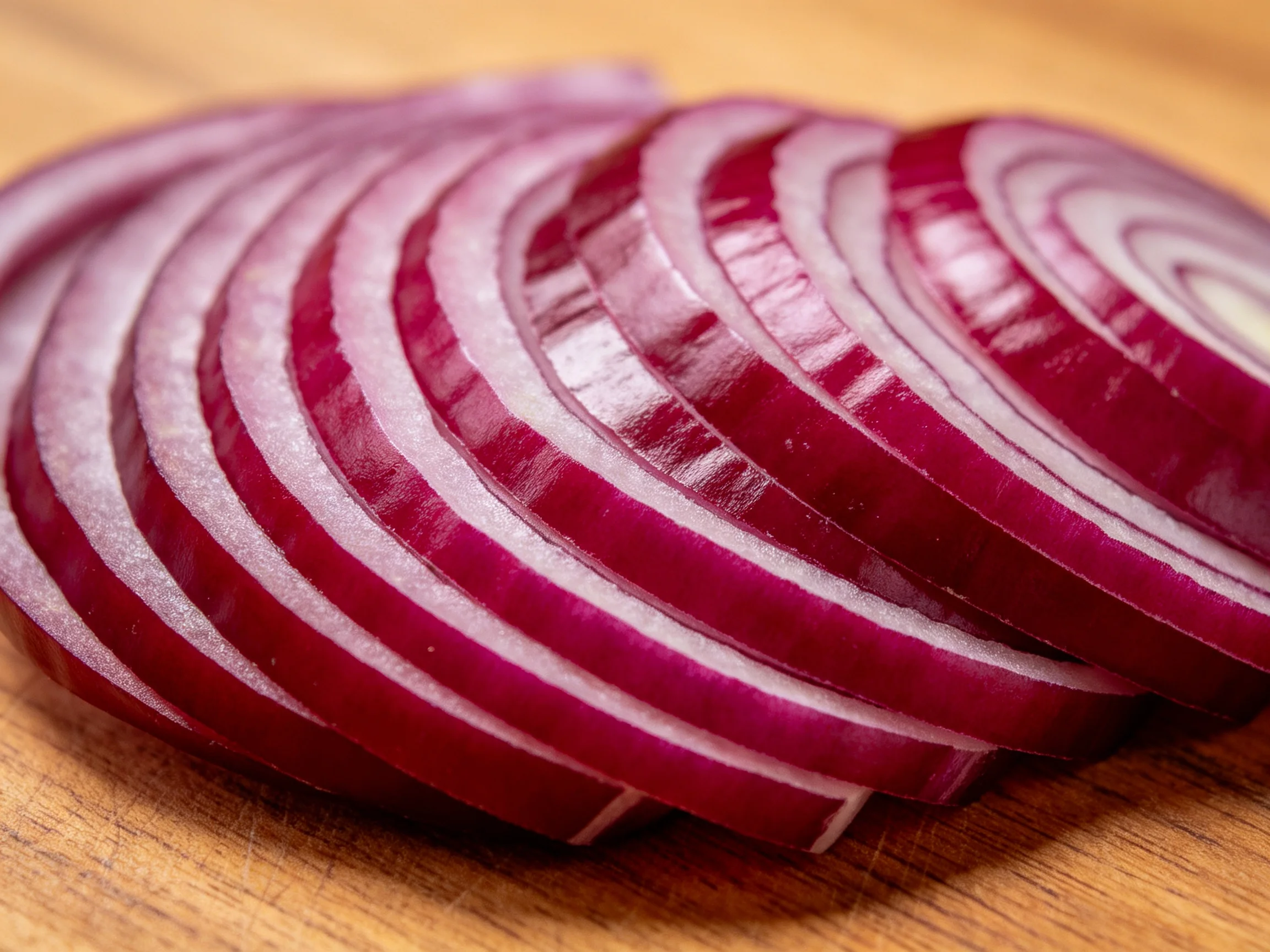 Sliced red onion rings neatly arranged on a wooden cutting board