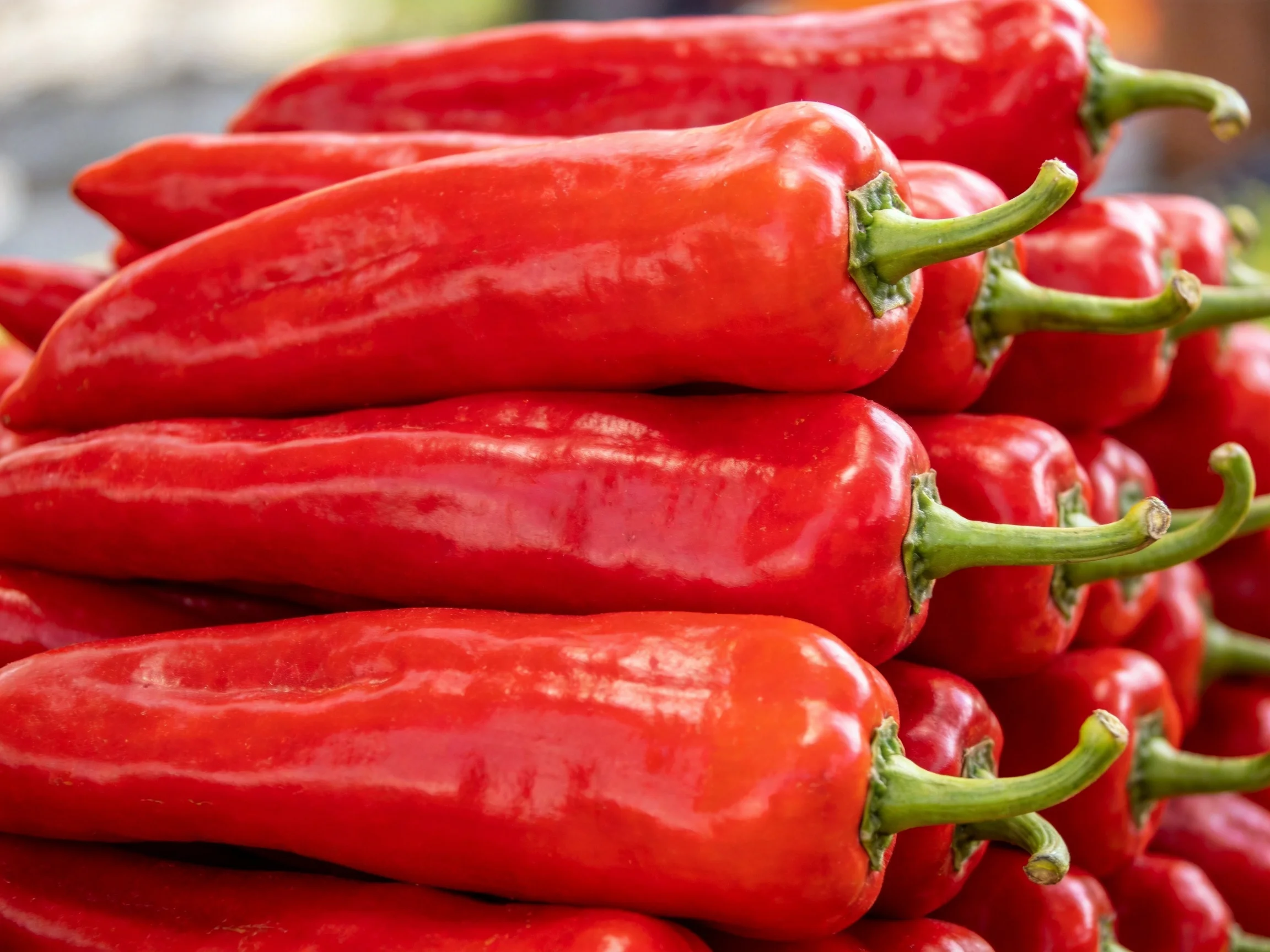 Stack of vibrant red chili peppers with green stems