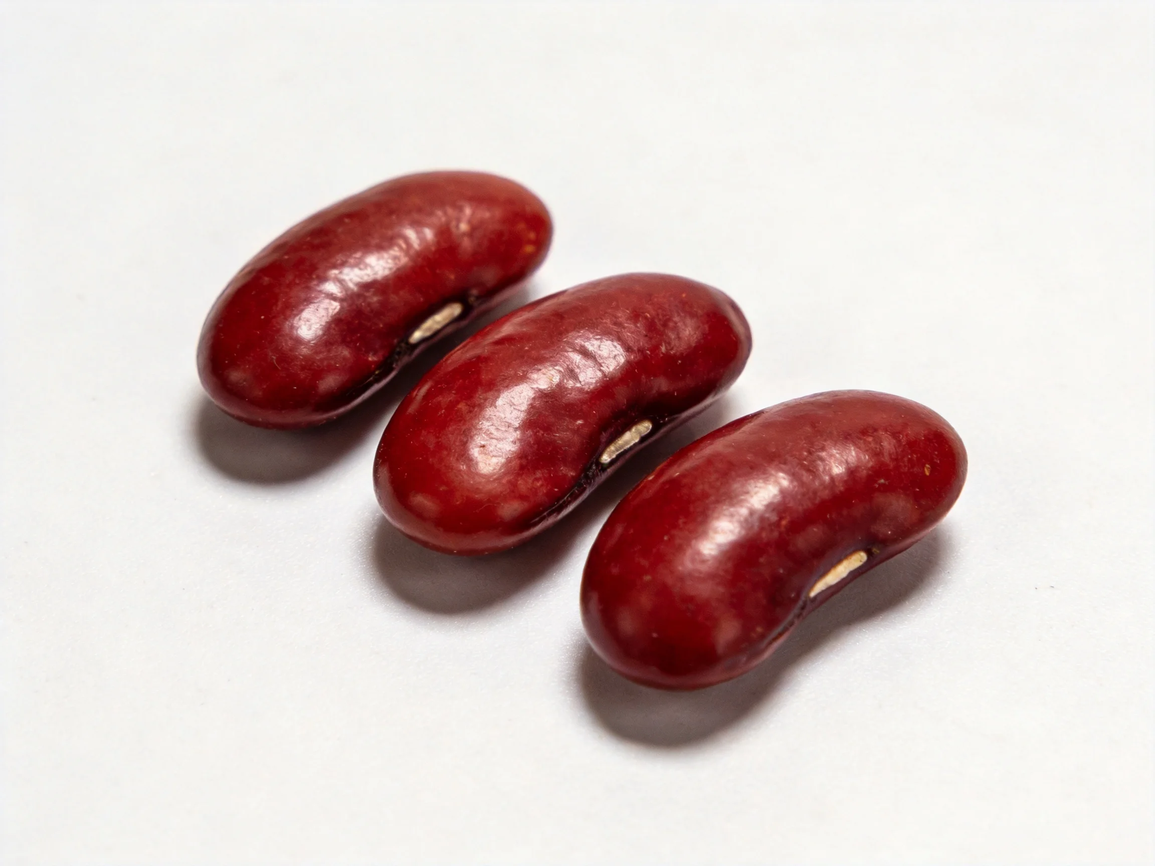 Three glossy red kidney beans arranged diagonally