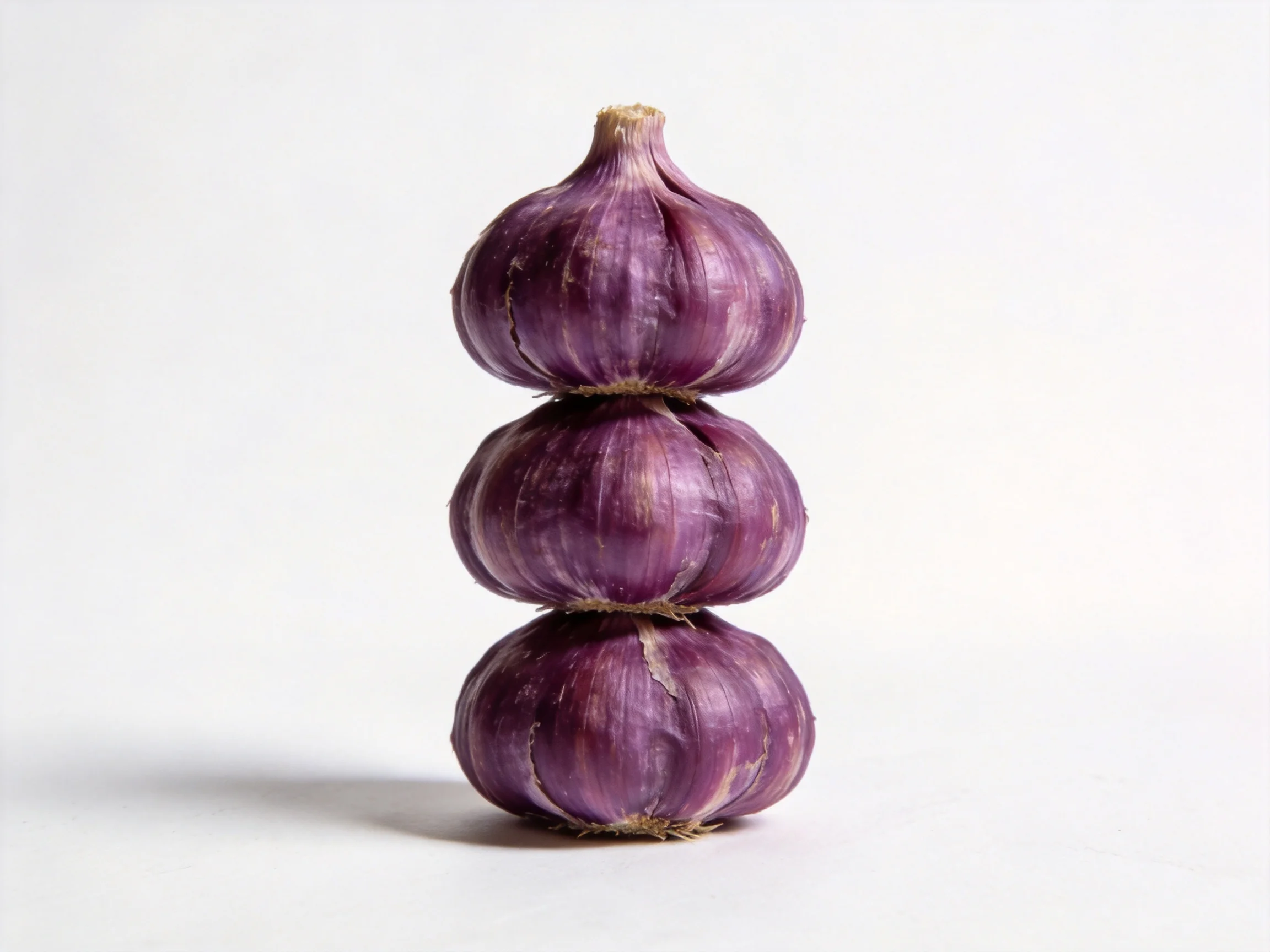 Three stacked purple garlic bulbs on a white background