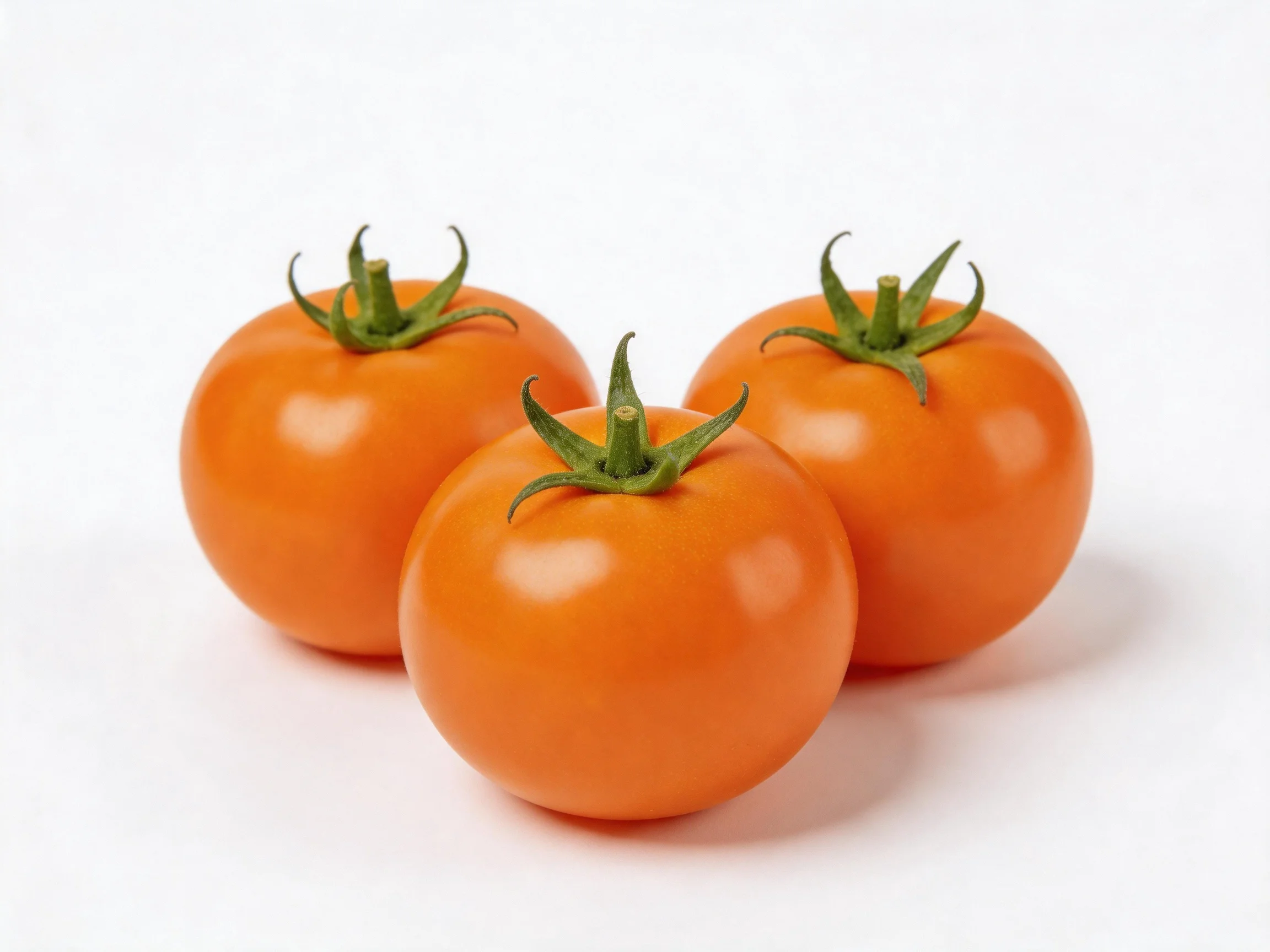 Three vibrant orange tomatoes with green stems arranged closely together